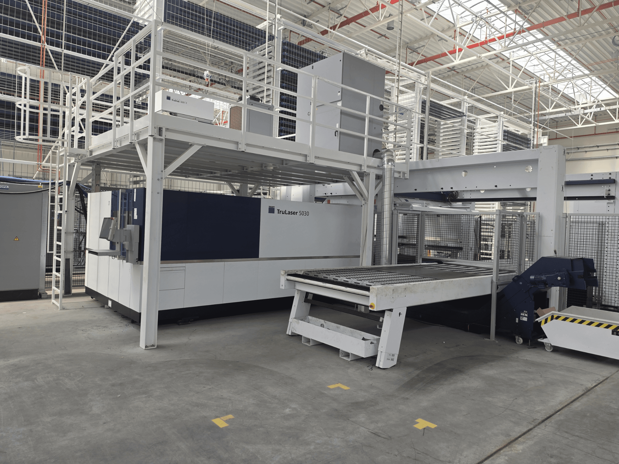 Máquina TRUMPF TruLaser 5030 fiber L76 FMC en un taller; vista frontal en la que se aprecian la zona de corte y el mecanismo de carga y descarga.