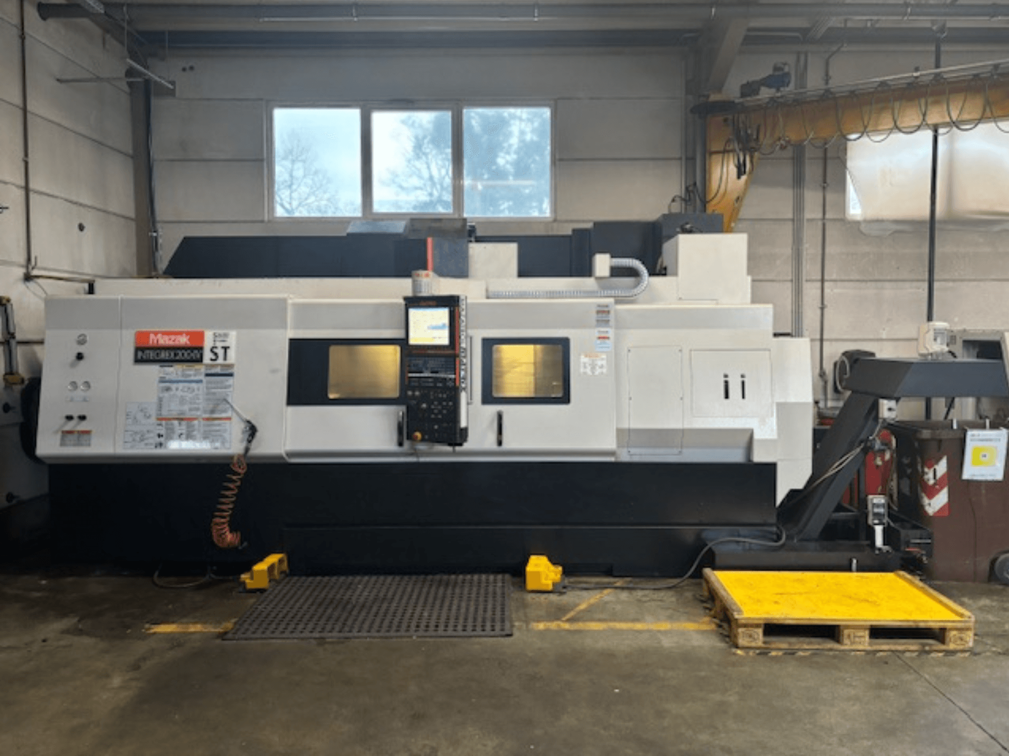 Mazak Integrex 200 SY ST, vista lateral, mostrando panel de control, pantallas de operación y líneas de refrigerante en un entorno de taller.