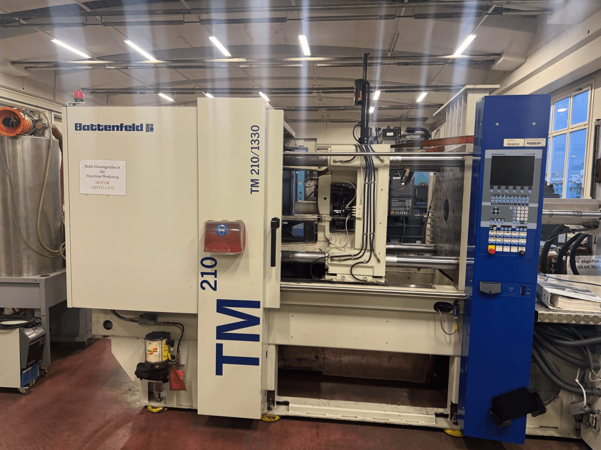 Máquina de moldeo por inyección hidráulica Battenfeld TM 210/1330, vista frontal, mostrando el panel de control y los componentes de la máquina.