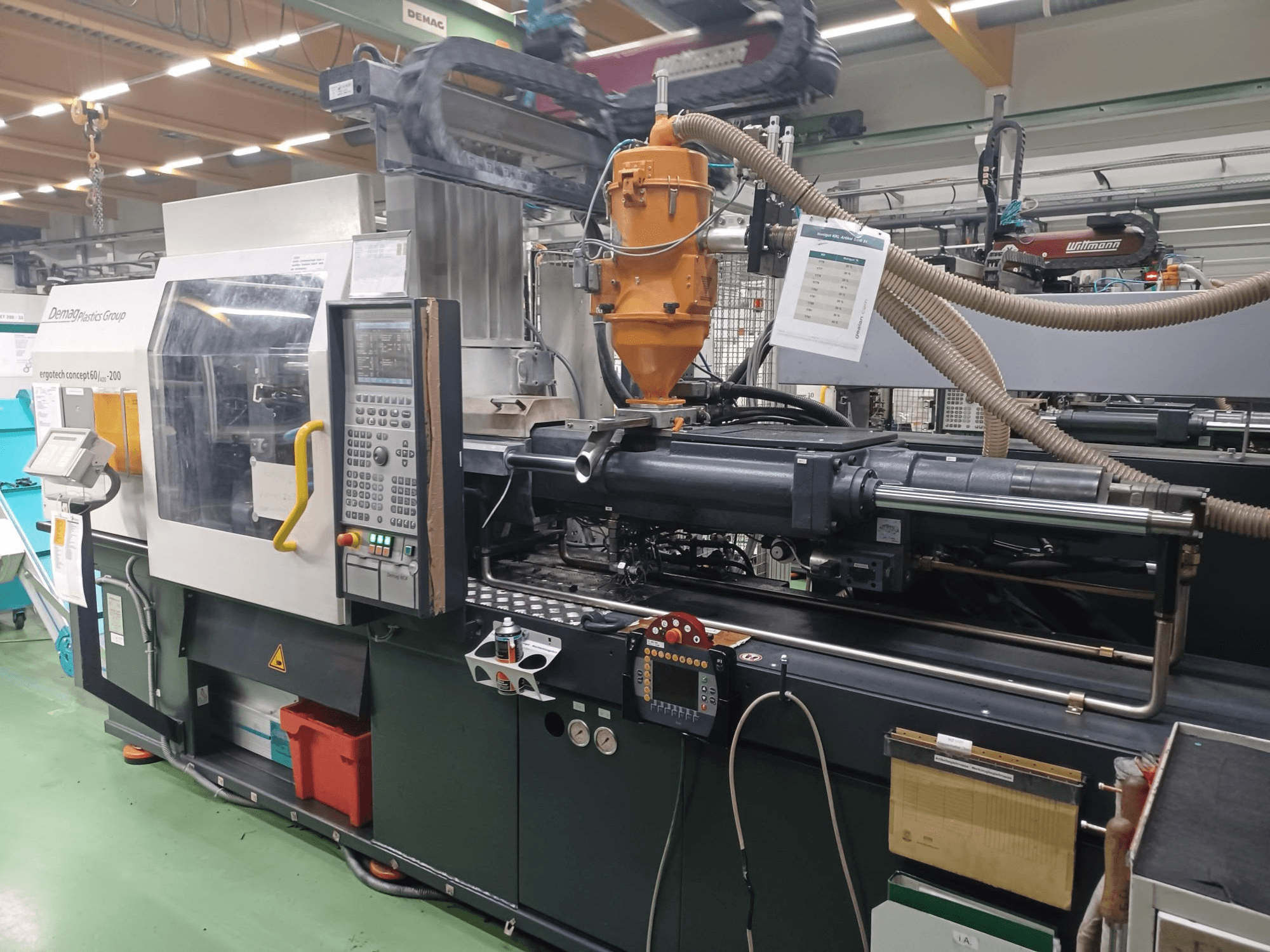 Máquina de moldeo por inyección Demag Ergotech 200, vista frontal, con panel de control, boquilla y componentes operativos visibles.