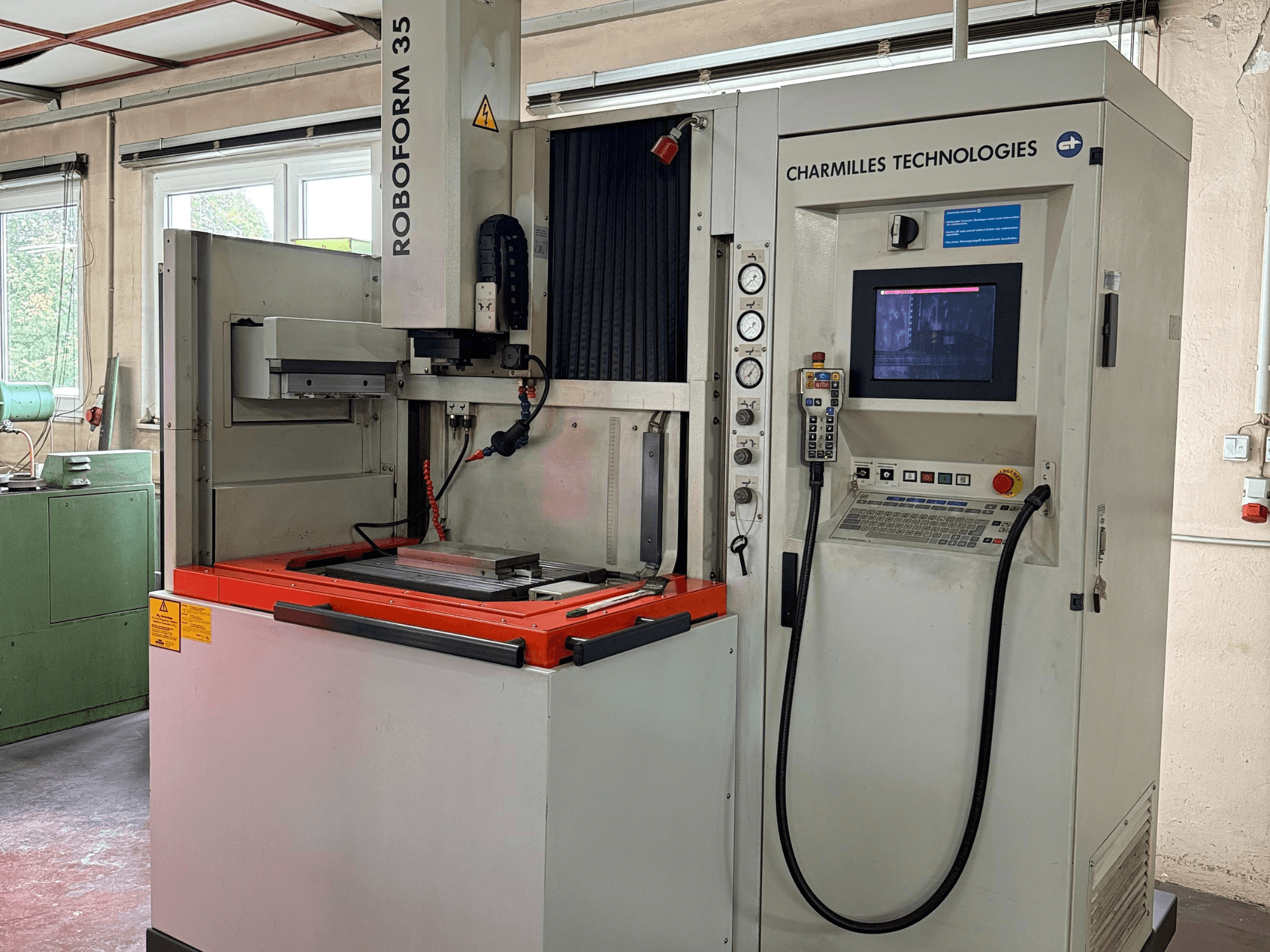 Máquina Roboforn 35 de Charmilles Technologies, vista frontal, mostrando el panel de control, las herramientas montadas y las etiquetas de seguridad.