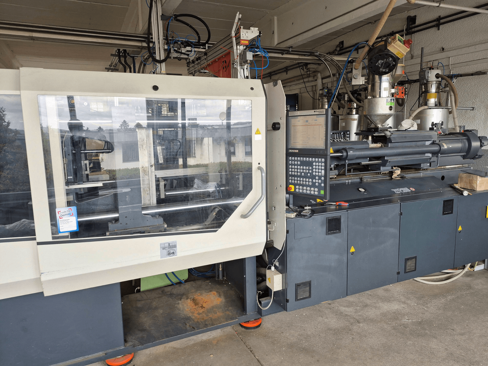 Máquina de moldeo por inyección hidráulica, SUMITOMO SHI DEMAG Systec 210/580-1450, vista frontal con el panel de control y los componentes visibles.