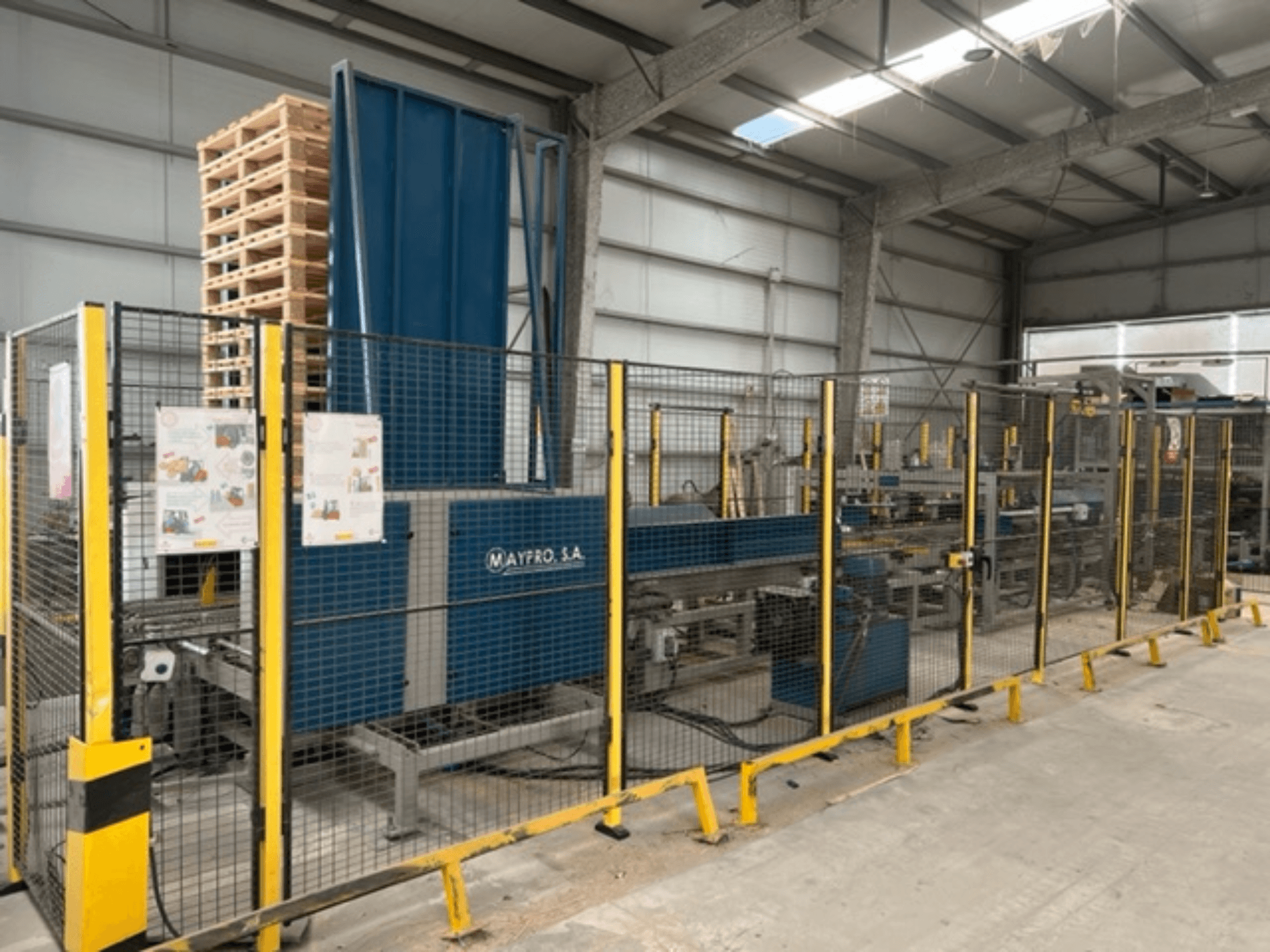 Envasadora industrial de palets de Maypro S.A. en un almacén, con malla de seguridad y controles operativos, vista lateral.