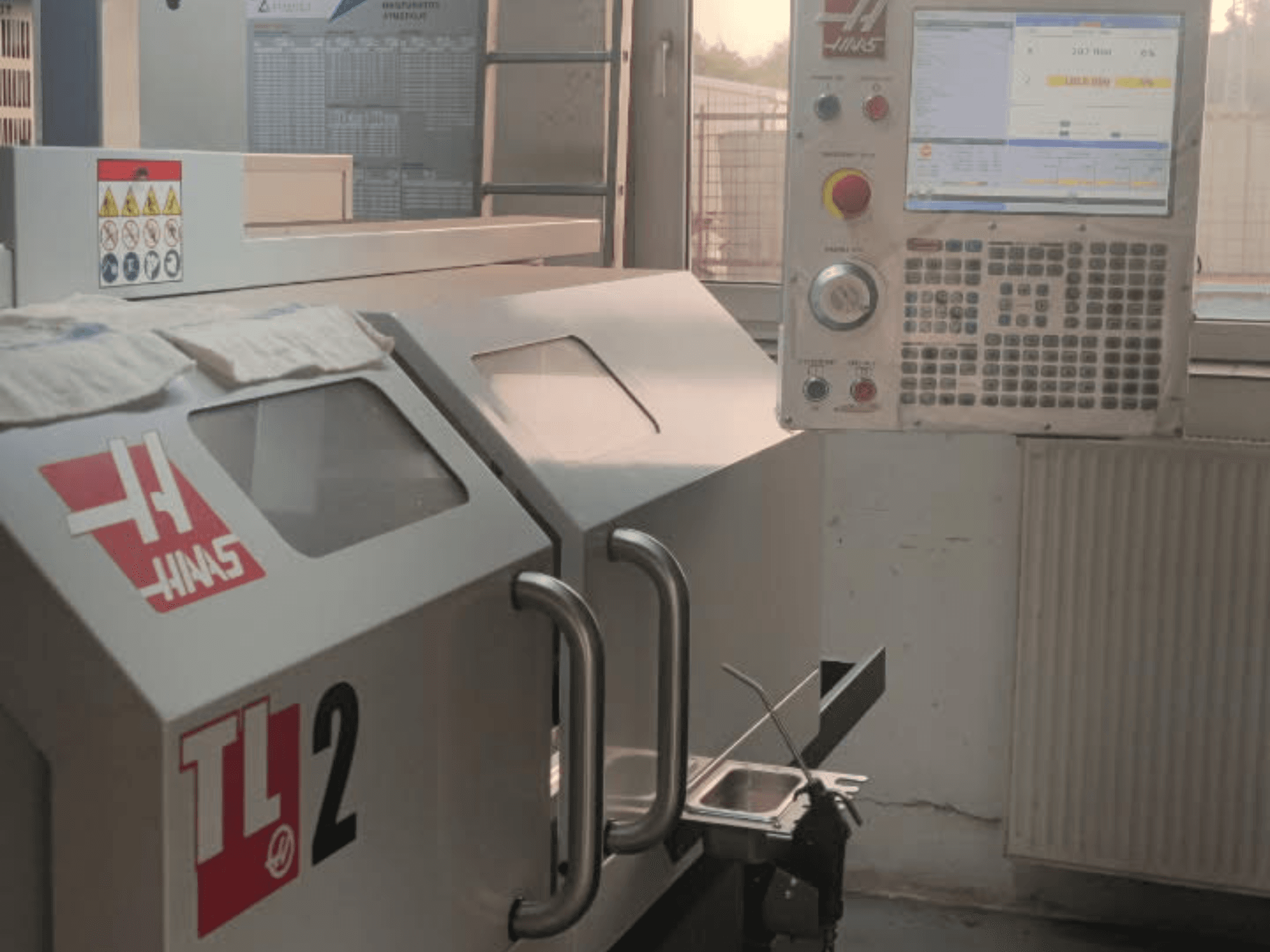 Vista frontal del torno horizontal Haas TL-2, con panel de control, carcasa metálica y señalización de seguridad.