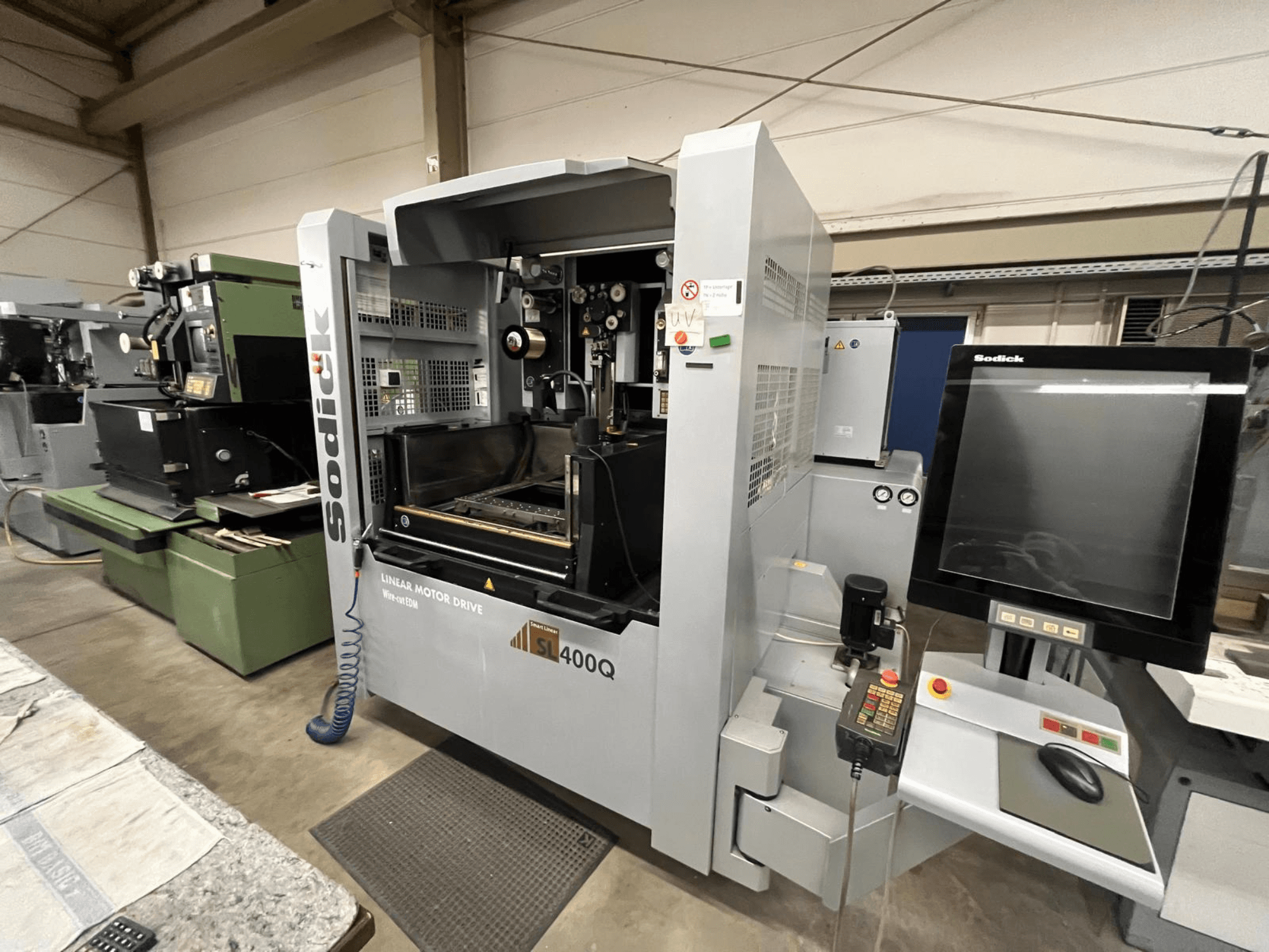 Máquina CNC con motor lineal Sodick SL400Q, vista frontal con panel de control digital y pantalla en un taller.