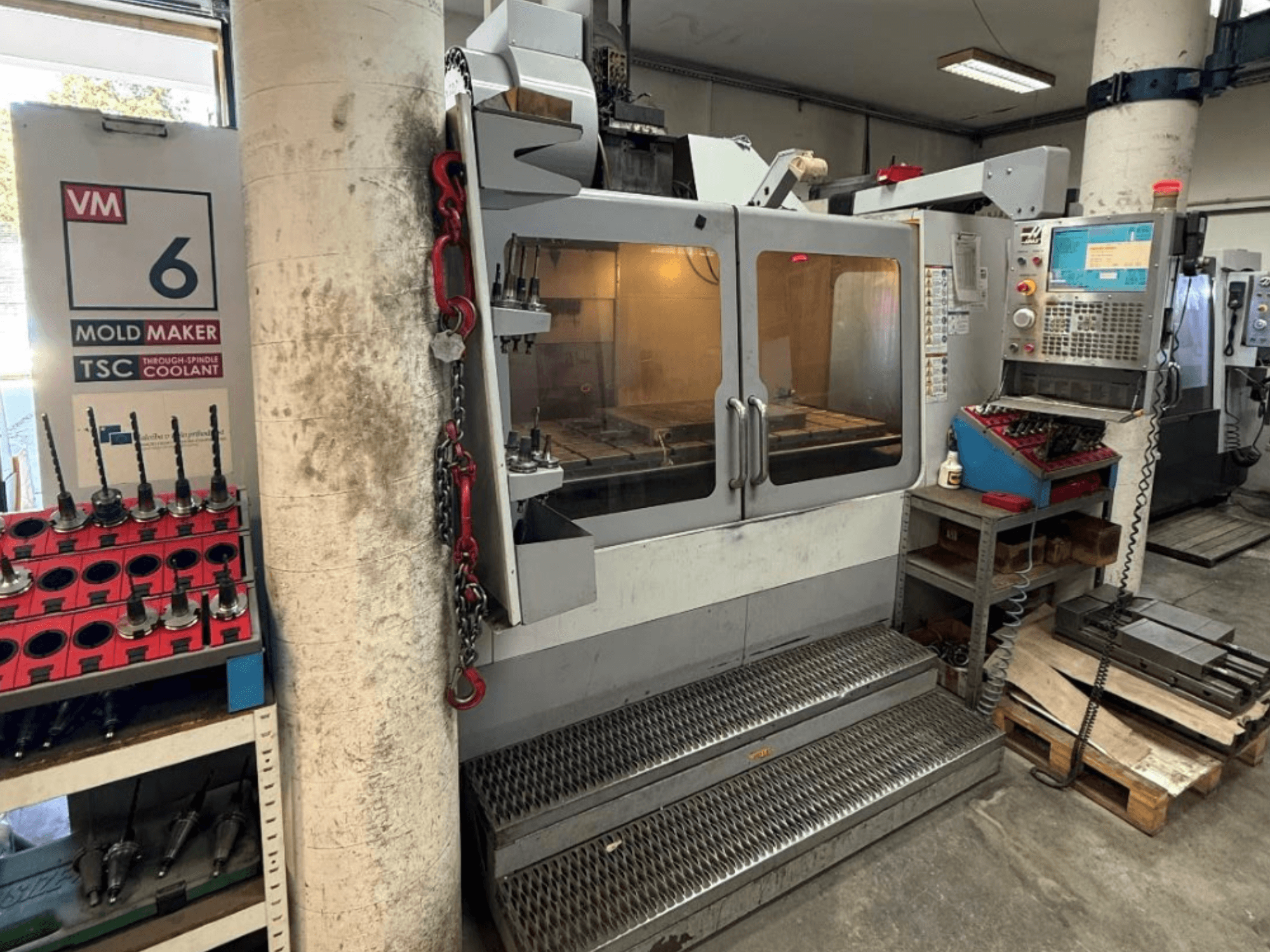 Centro de mecanizado vertical HAAS VM-6 HE en vista frontal, en la que se aprecian los mandos, el sistema de refrigeración y el almacén de herramientas.