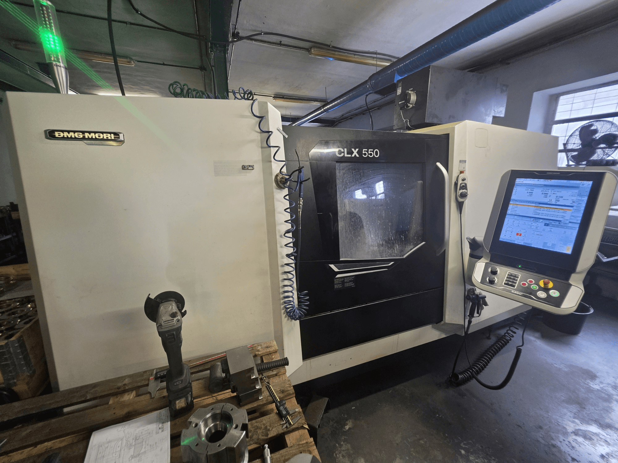 Torno horizontal DMG MORI CLX 550 V3, vista frontal en la que se aprecian el panel de control, las herramientas de corte y la carcasa de la máquina.