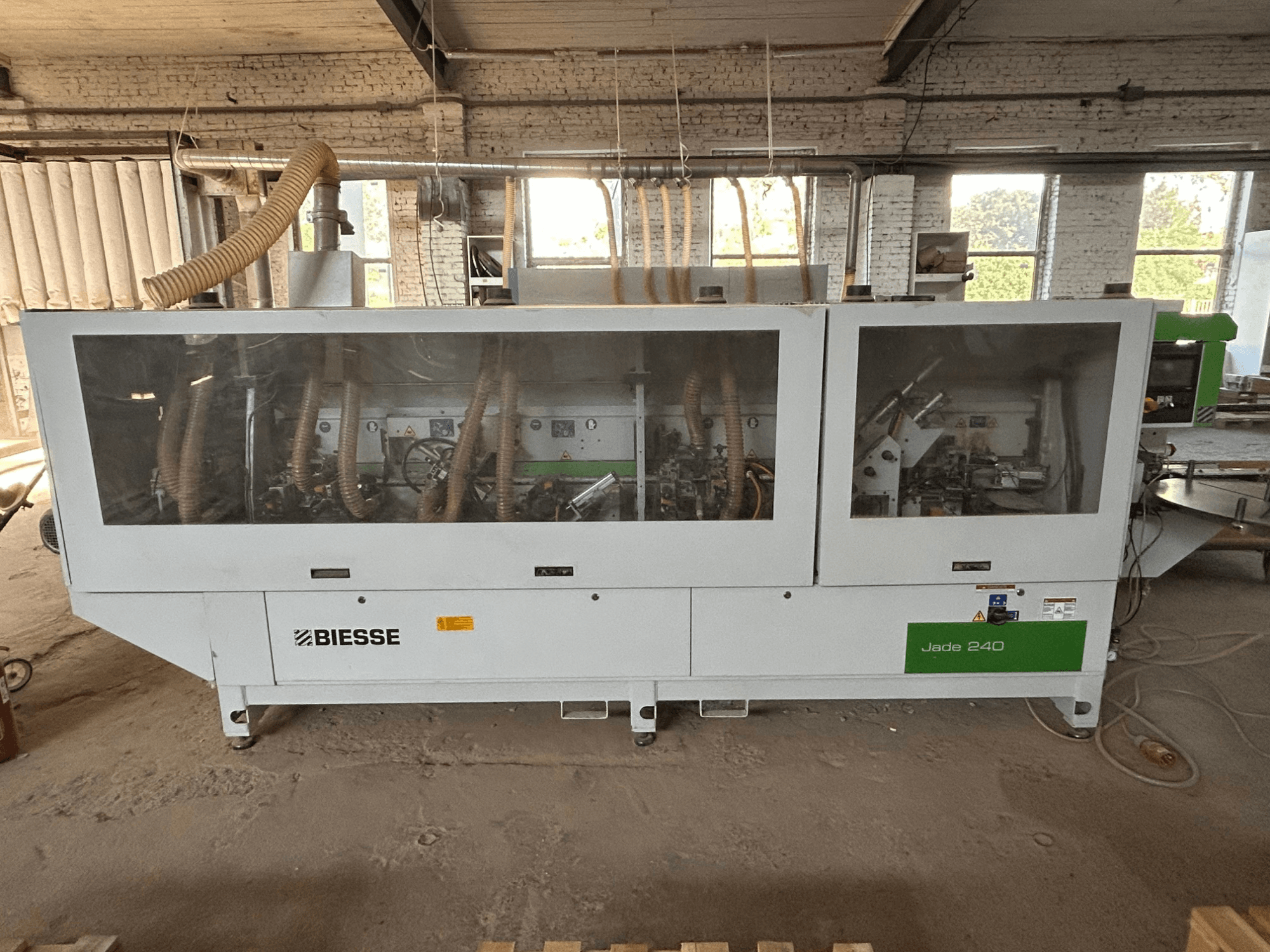 Chapeadora BIESSE Jade 240 en blanco y verde; vista frontal en la que se aprecian el panel de control y los detalles del interior de la máquina.