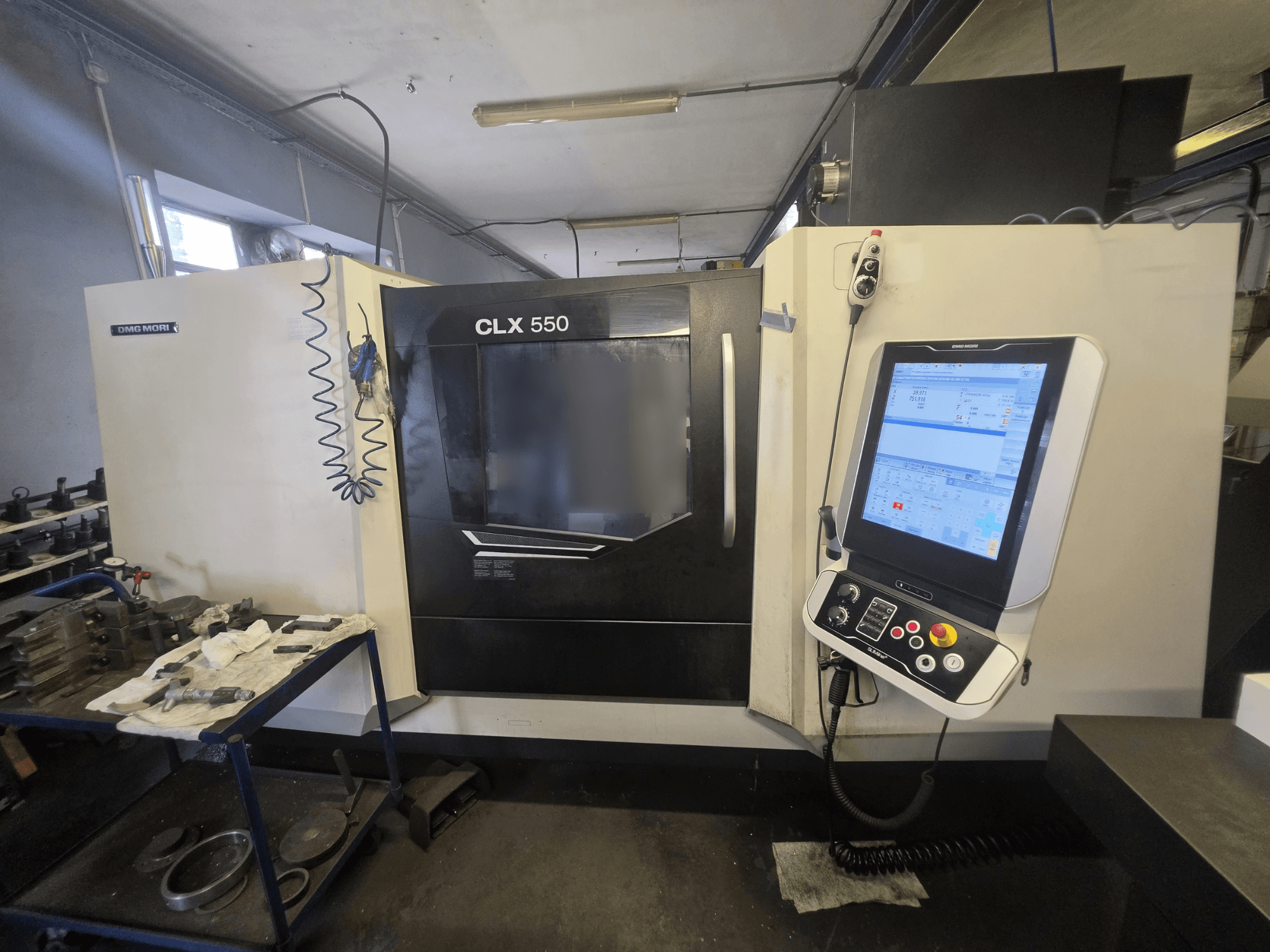 Torno horizontal DMG MORI CLX 550 V3, vista frontal, en la que se aprecian el panel de control y el espacio de trabajo con las herramientas.