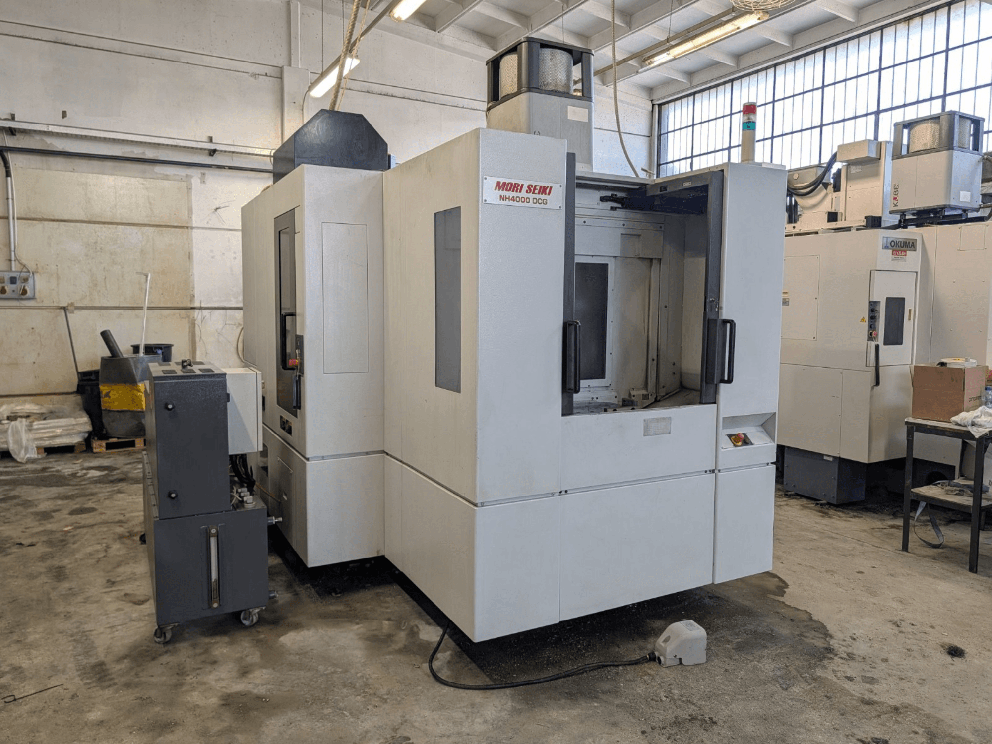 Centro de mecanizado horizontal MORI SEIKI NH 4000 DCG, vista frontal, mostrando el panel de control y el área de trabajo, acabado gris y blanco.