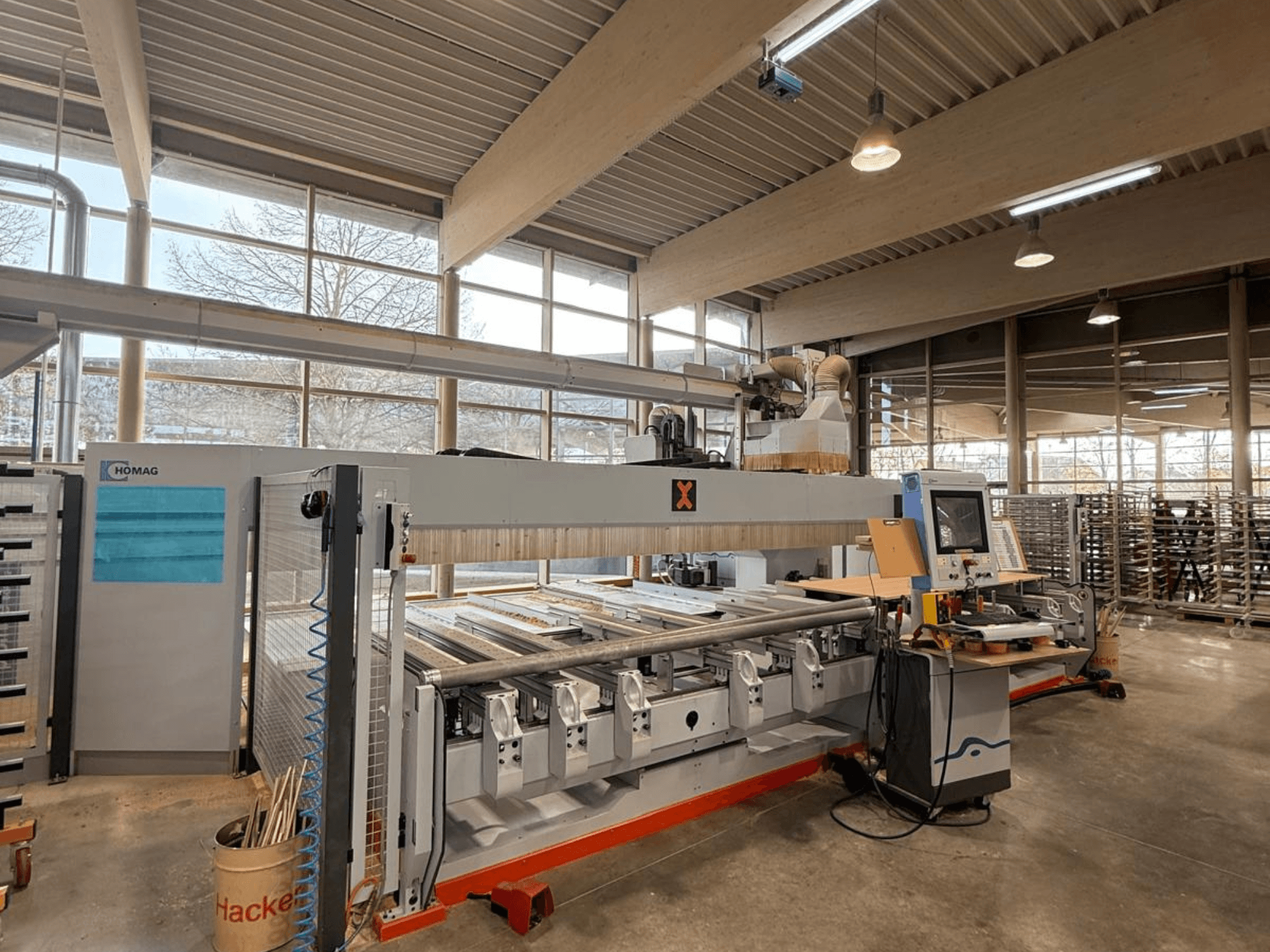 Máquina CNC HOMAG en un taller, vista frontal, mostrando un panel de control y múltiples ranuras para herramientas para trabajos de precisión en madera.