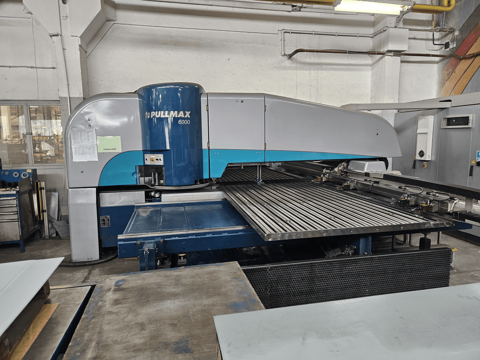 Vista frontal de la punzonadora CNC Pullmax 6000, mostrando su gran base plana y su estructura metálica en un entorno de taller.