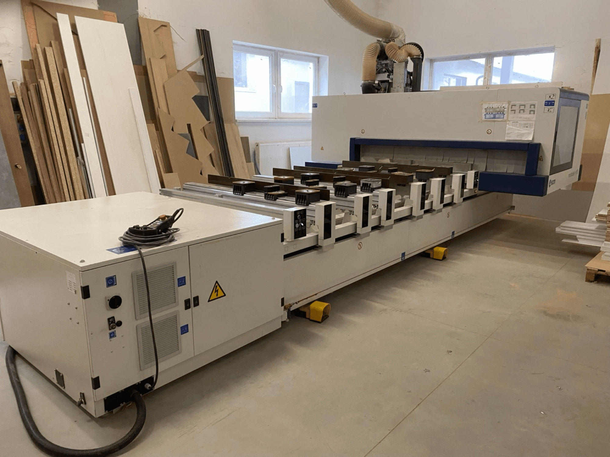 Centro de mecanizado de madera CNC SCM Morbidelli Author M100 en un taller, en el que se muestra una vista frontal con el panel de control y el sistema de aspiración de polvo.