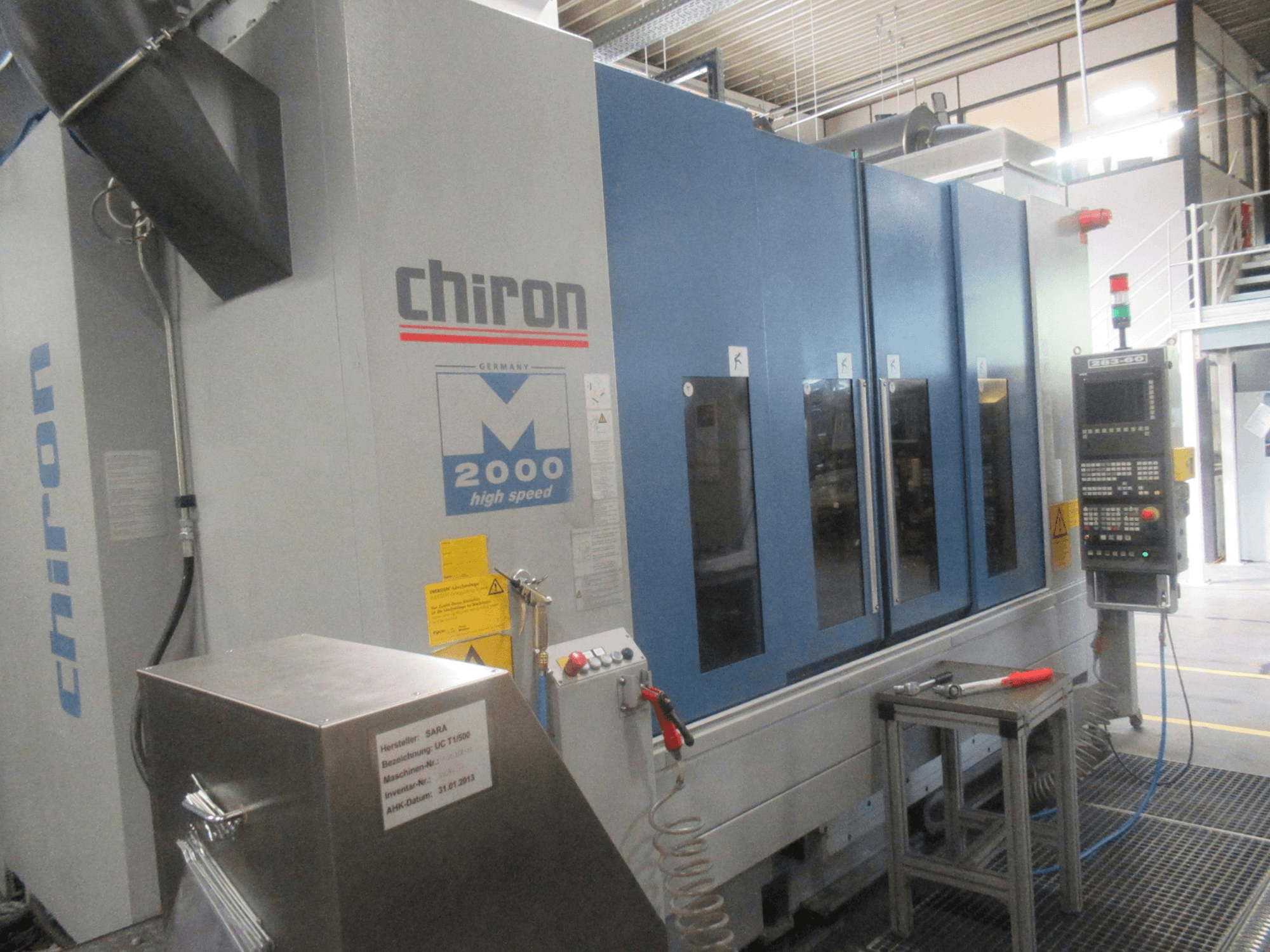 Centro de mecanizado vertical CHIRON Mill 2000, vista frontal con el panel de control, diseño en azul y características de alta velocidad visibles.