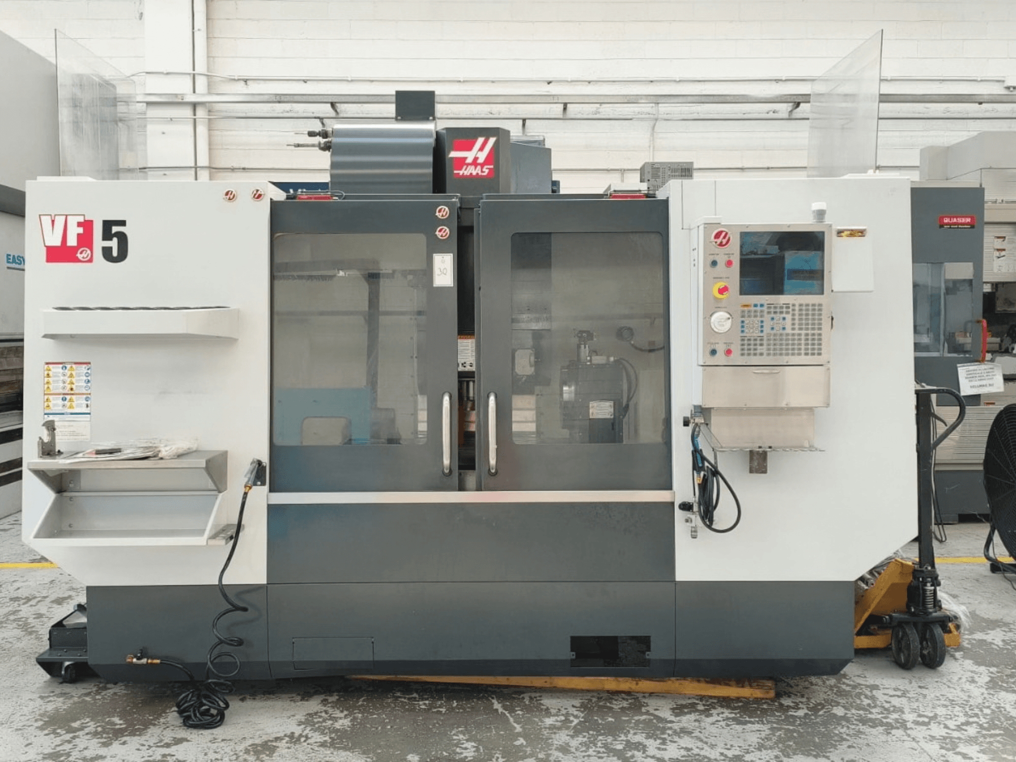 Vista frontal del centro de mecanizado vertical HAAS VF 5/40, en la que se aprecian el panel de control y las puertas de cristal.