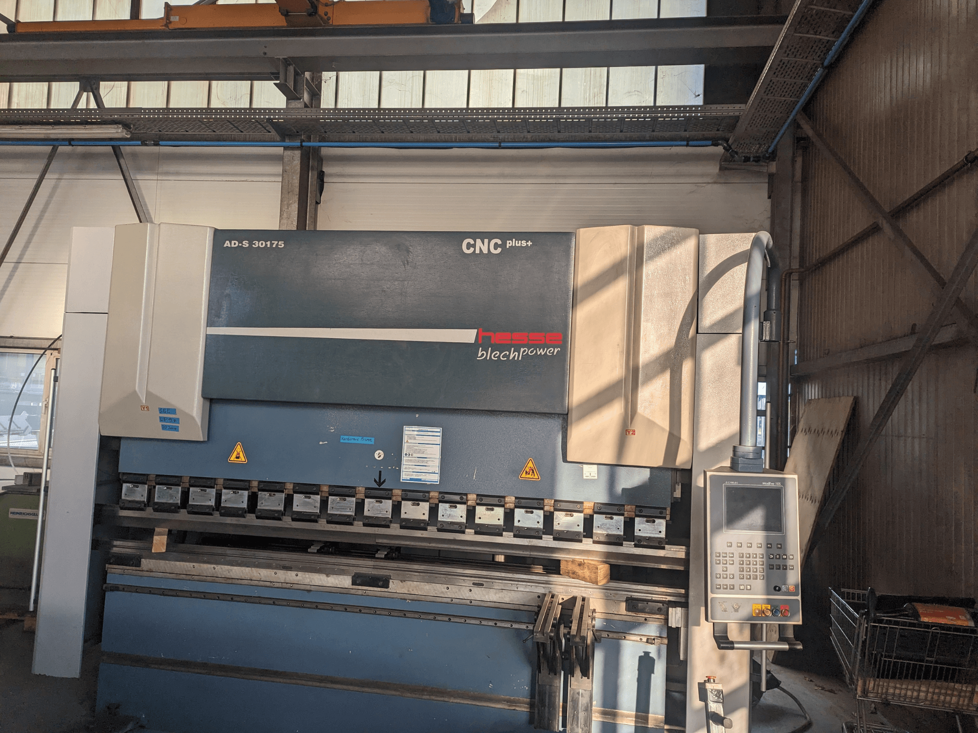 Plegadora CNC AD-S 30175 de Hesse, vista frontal, con panel de control y herramientas, colocada en un entorno de taller.