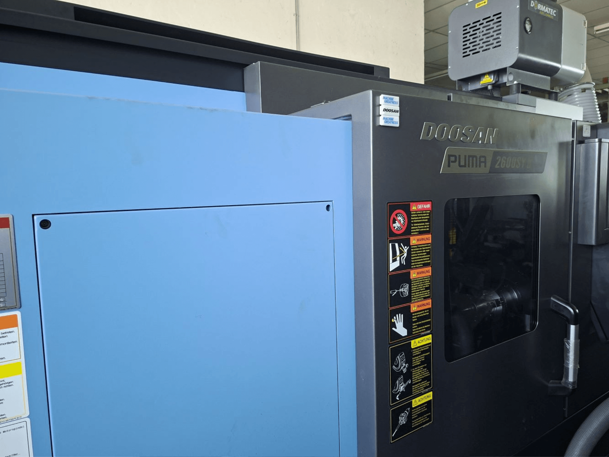 Tornos horizontales DOOSAN PUMA 2600 SY II, vista frontal, mostrando las etiquetas de seguridad y los paneles azules.