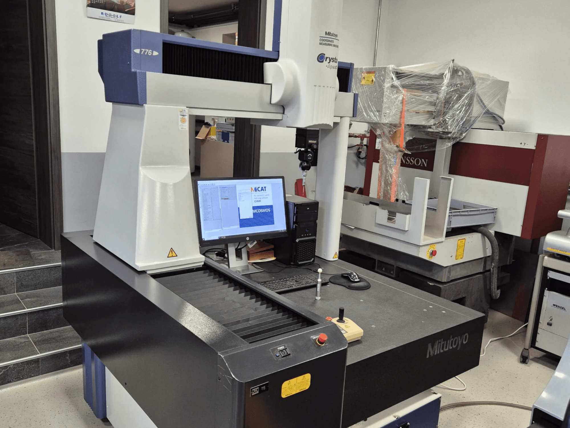 Máquina de medición de coordenadas Mitutoyo modelo 776 en vista frontal, con un monitor que muestra el software de medición y los controles visibles.