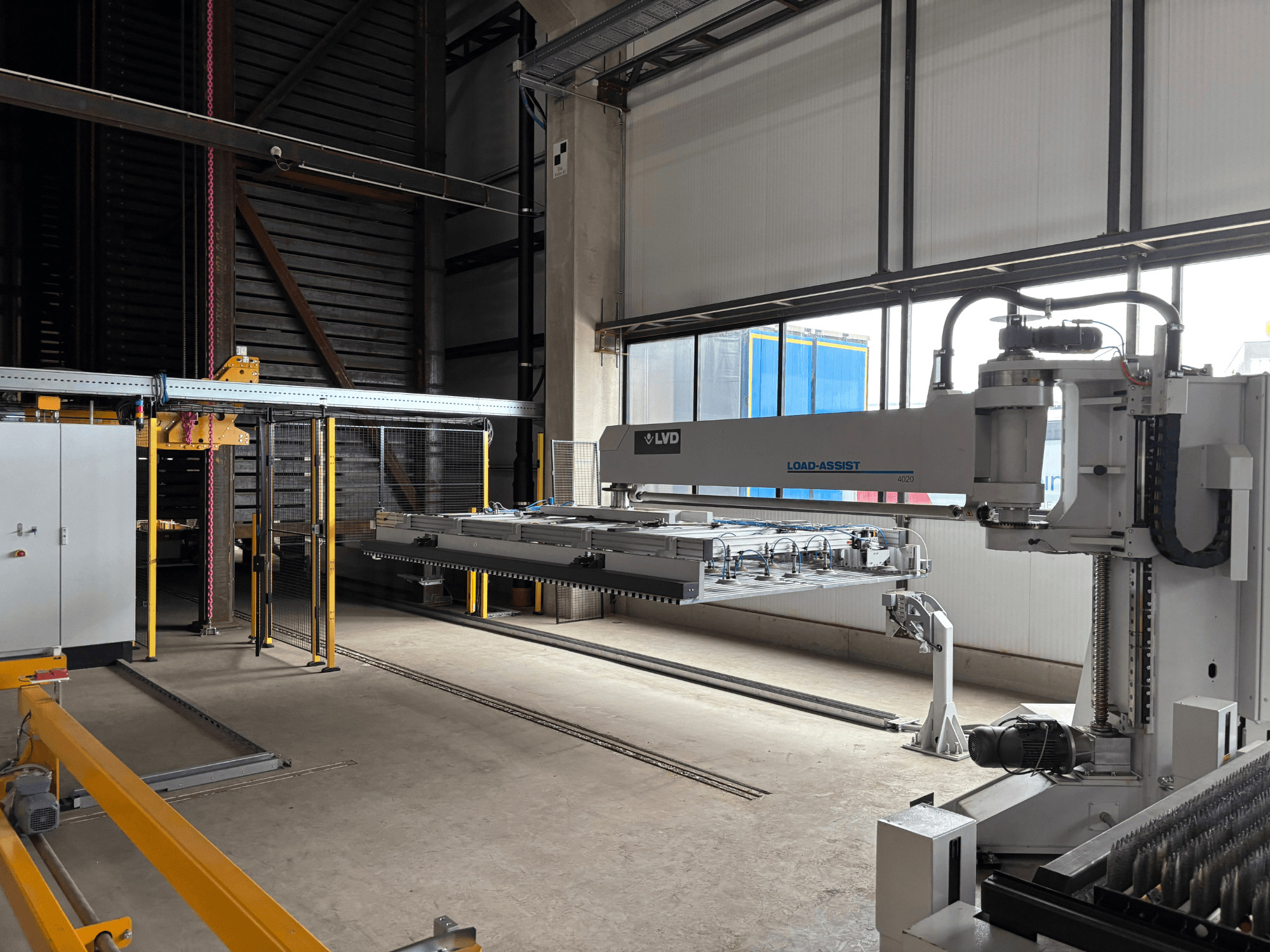 Equipo de automatización LVD Load-Assist 4020 en una vista frontal con un brazo robótico y un sistema de carga visibles en un amplio espacio de trabajo.