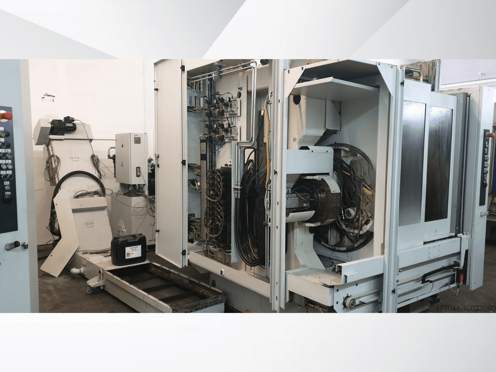 Maquinaria industrial con cableado expuesto, panel de control y componentes mecánicos; vista lateral de una máquina compleja.