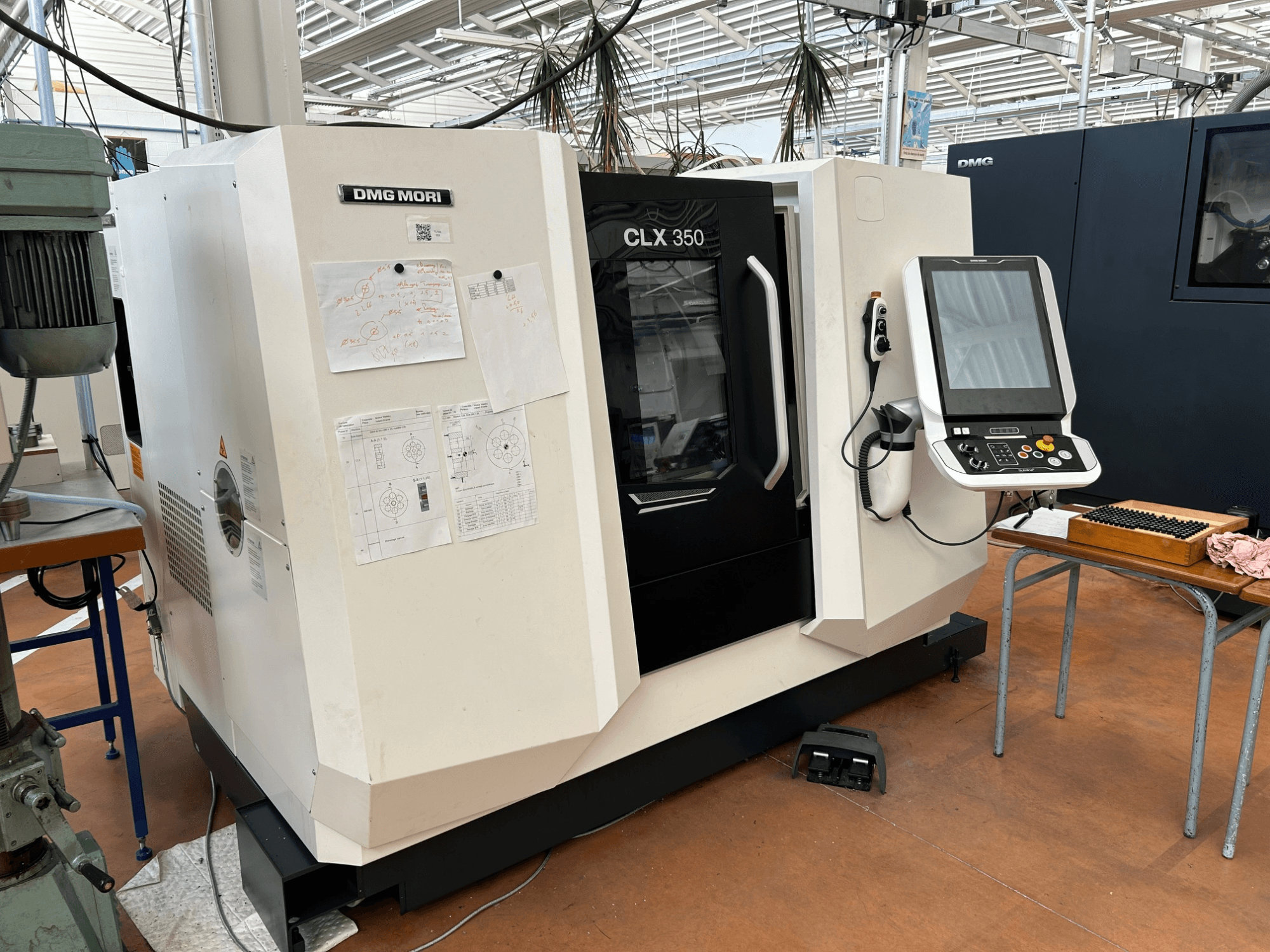 Torno horizontal DMG MORI CLX 350 V4, vista frontal con el panel de control y la documentación técnica adjunta.