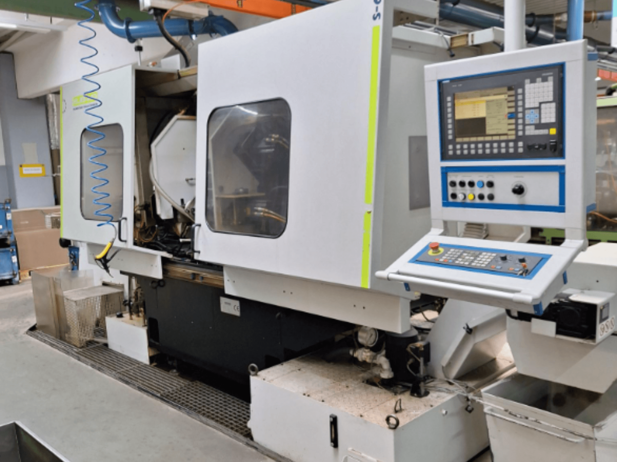 Fresadora industrial con panel de control, vista lateral, con cámaras dobles y conexiones de tuberías visibles.