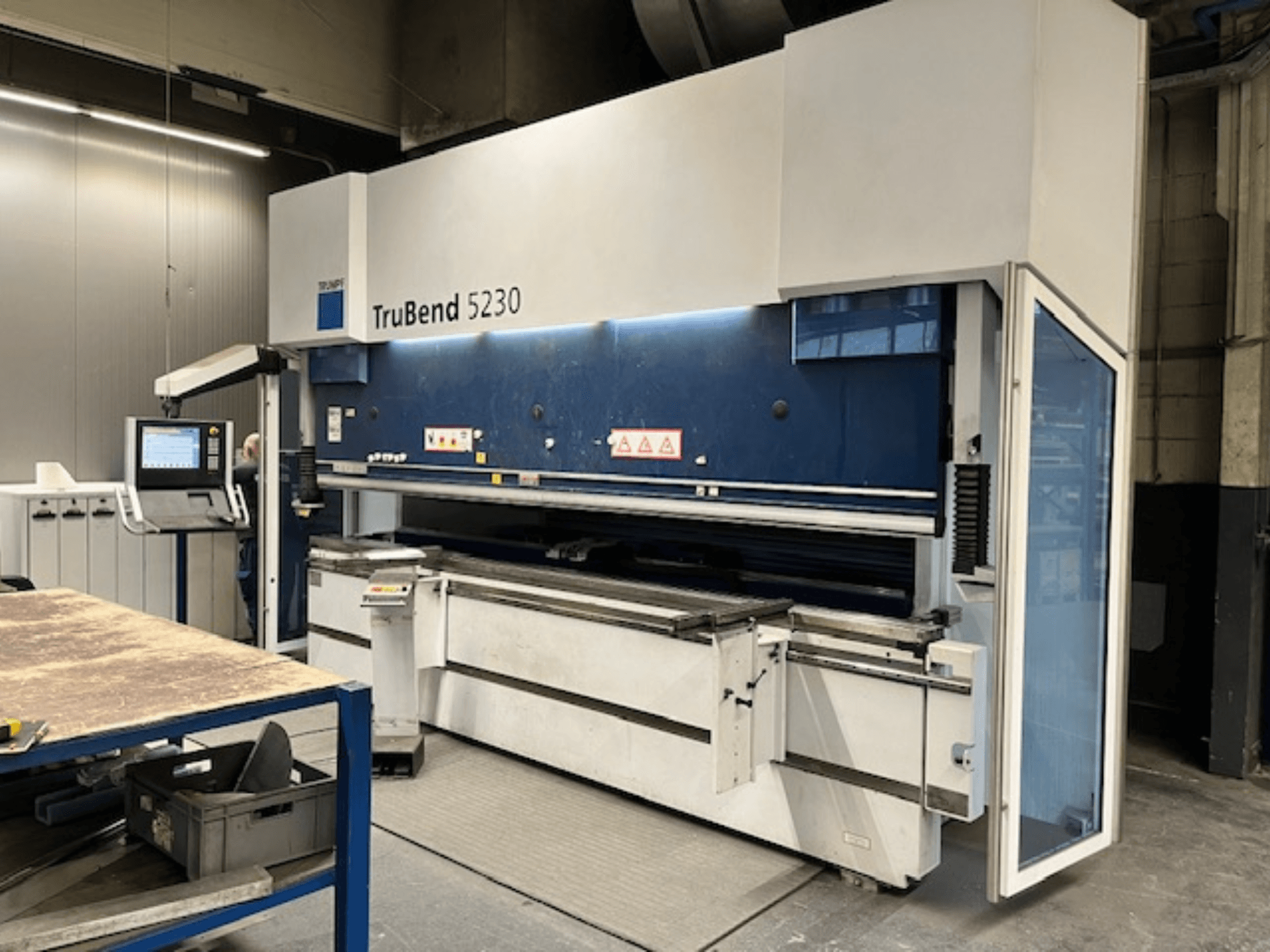 Plegadora TruBend 5230 en entorno industrial; vista frontal que muestra el panel de control, los dispositivos de seguridad y la mesa de trabajo.
