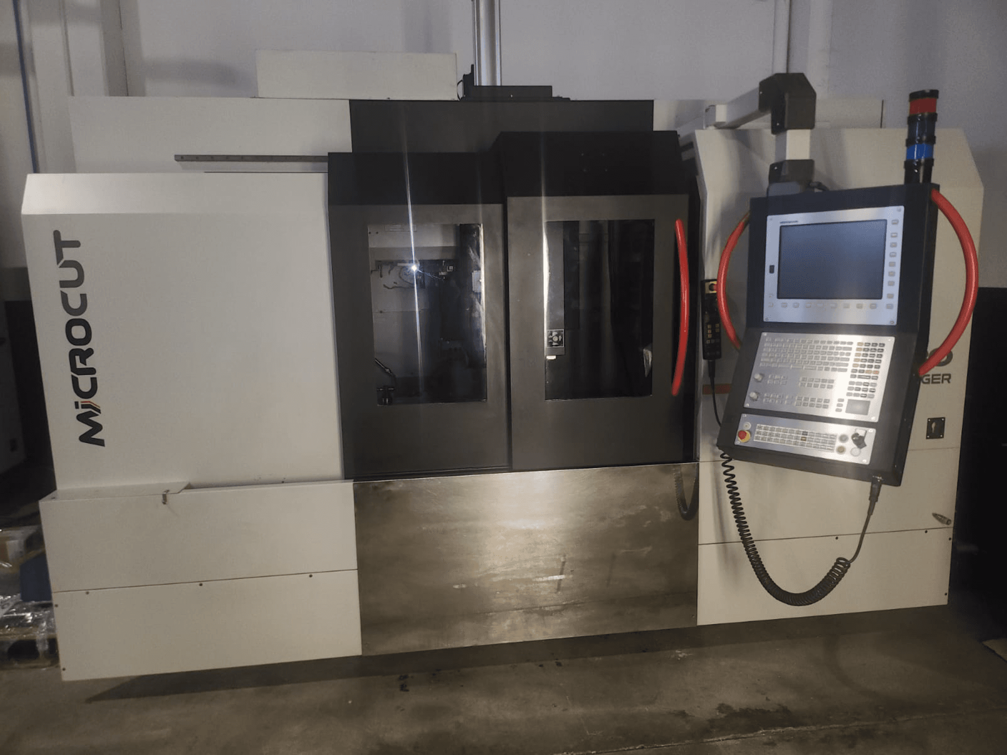 Máquina CNC de microcorte vista de frente; presenta panel de control, ventanas dobles, diseño industrial y acabado metálico.