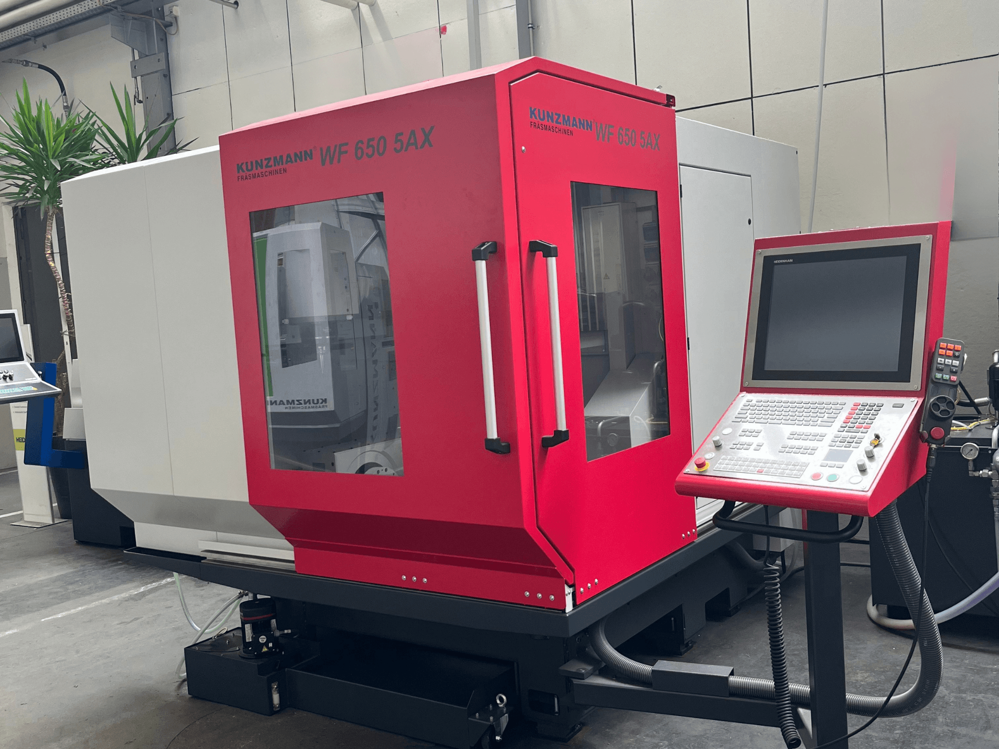 Centro de mecanizado vertical KUNZMANN WF 650 5AX de color rojo, vista frontal con panel de control y pantalla táctil, ubicado en un taller.