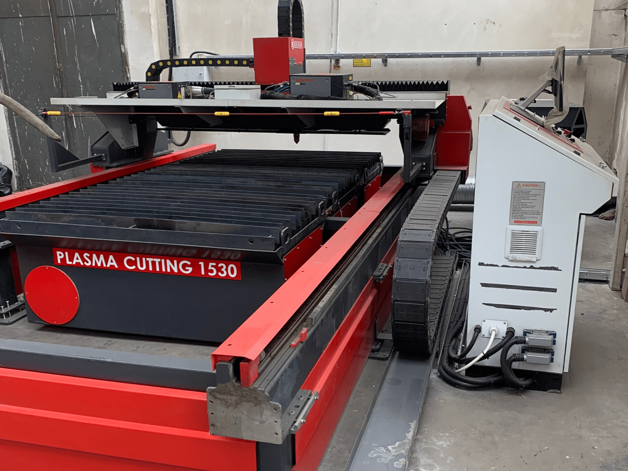 Máquina de corte por plasma DENER PL 1530; vista lateral en la que se aprecian la mesa de corte, el panel de control y las conexiones eléctricas.