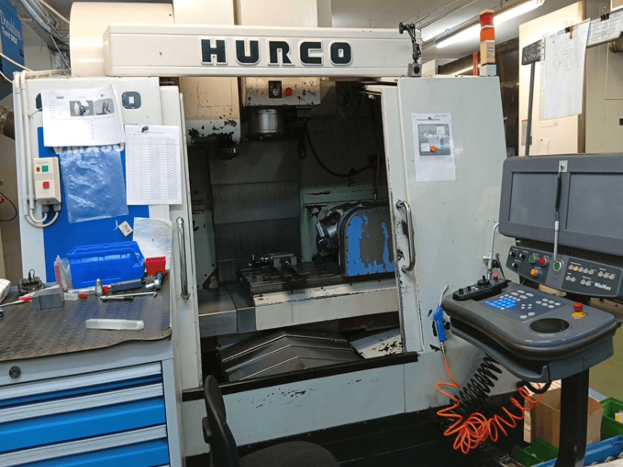 Centro de mecanizado vertical Hurco VMX 30T, vista frontal, mostrando el panel de control, el espacio de trabajo y la puerta parcialmente abierta.