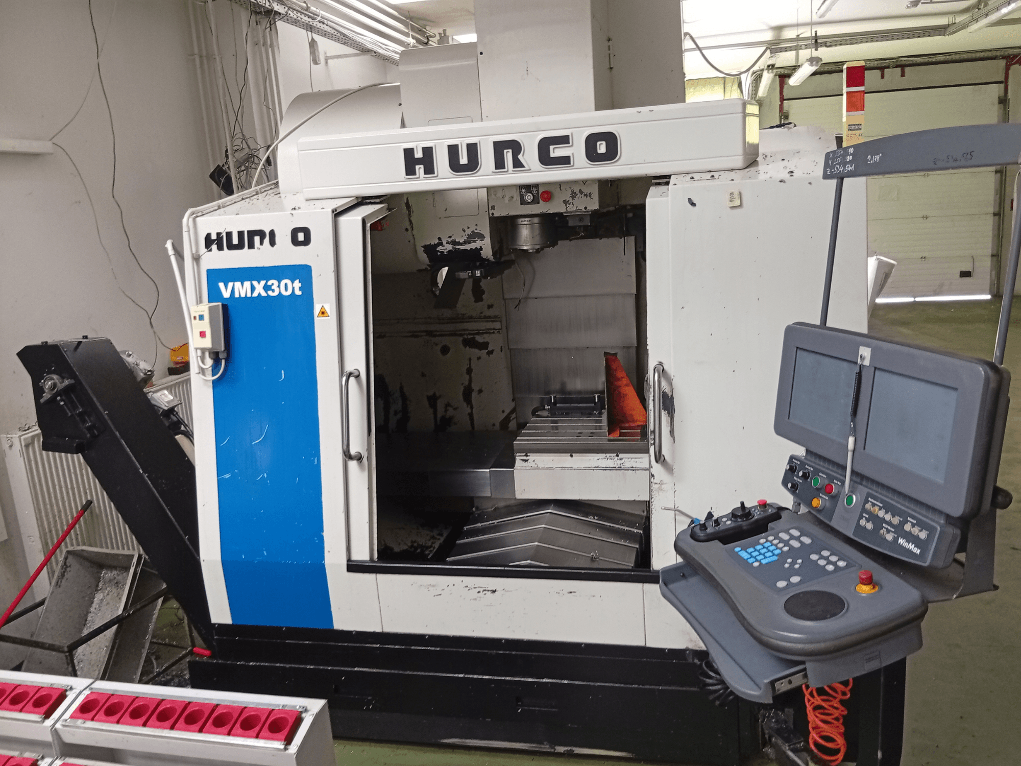 Centro de mecanizado vertical Hurco VMX 30T, vista frontal, en la que se aprecian el panel de control y la zona del husillo, con la mesa de trabajo a la vista.