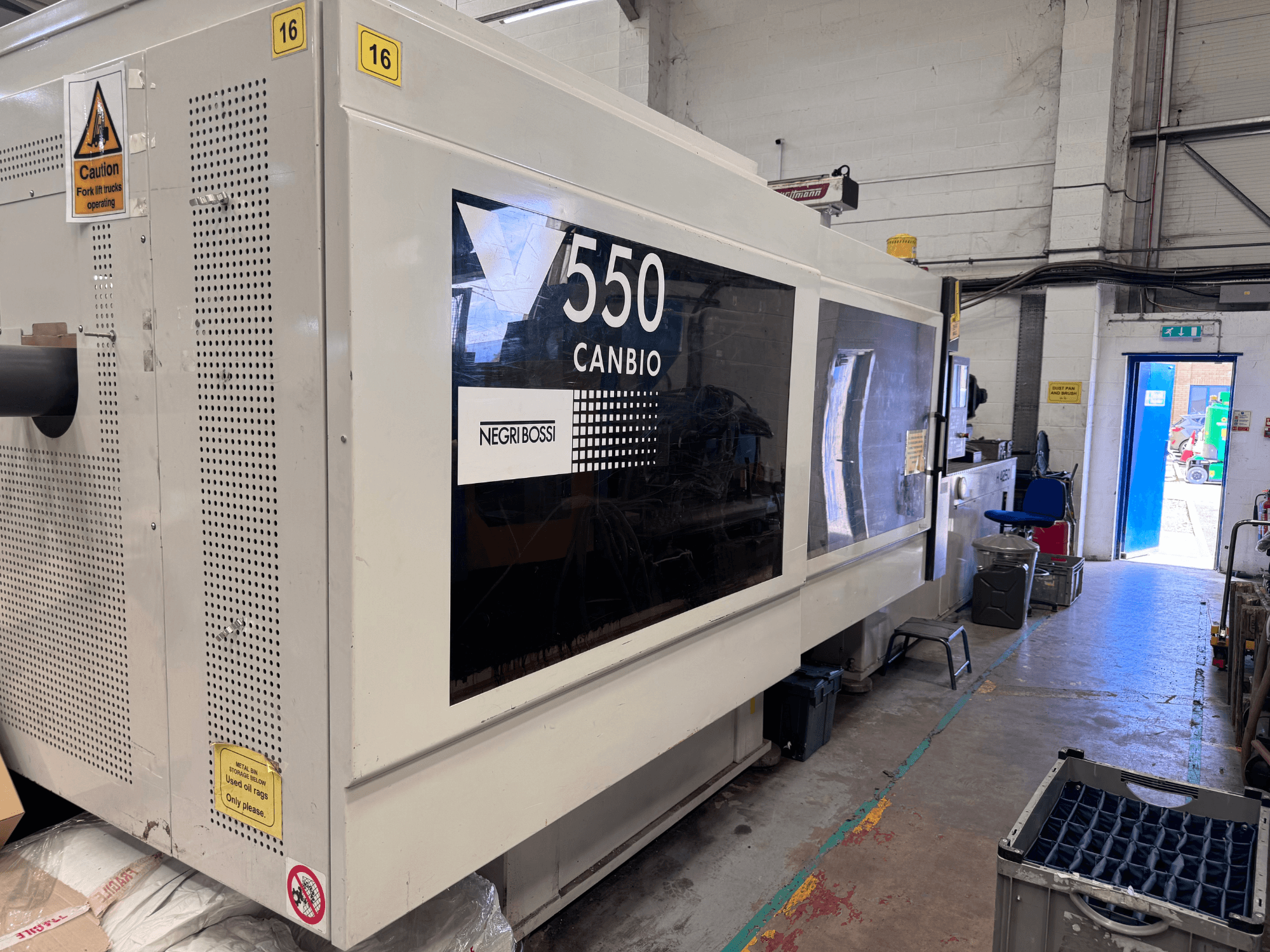 Máquina de moldeo por inyección hidráulica Negri Bossi 5500H-4250, vista frontal en la que se aprecian el panel de control y las señales de advertencia.