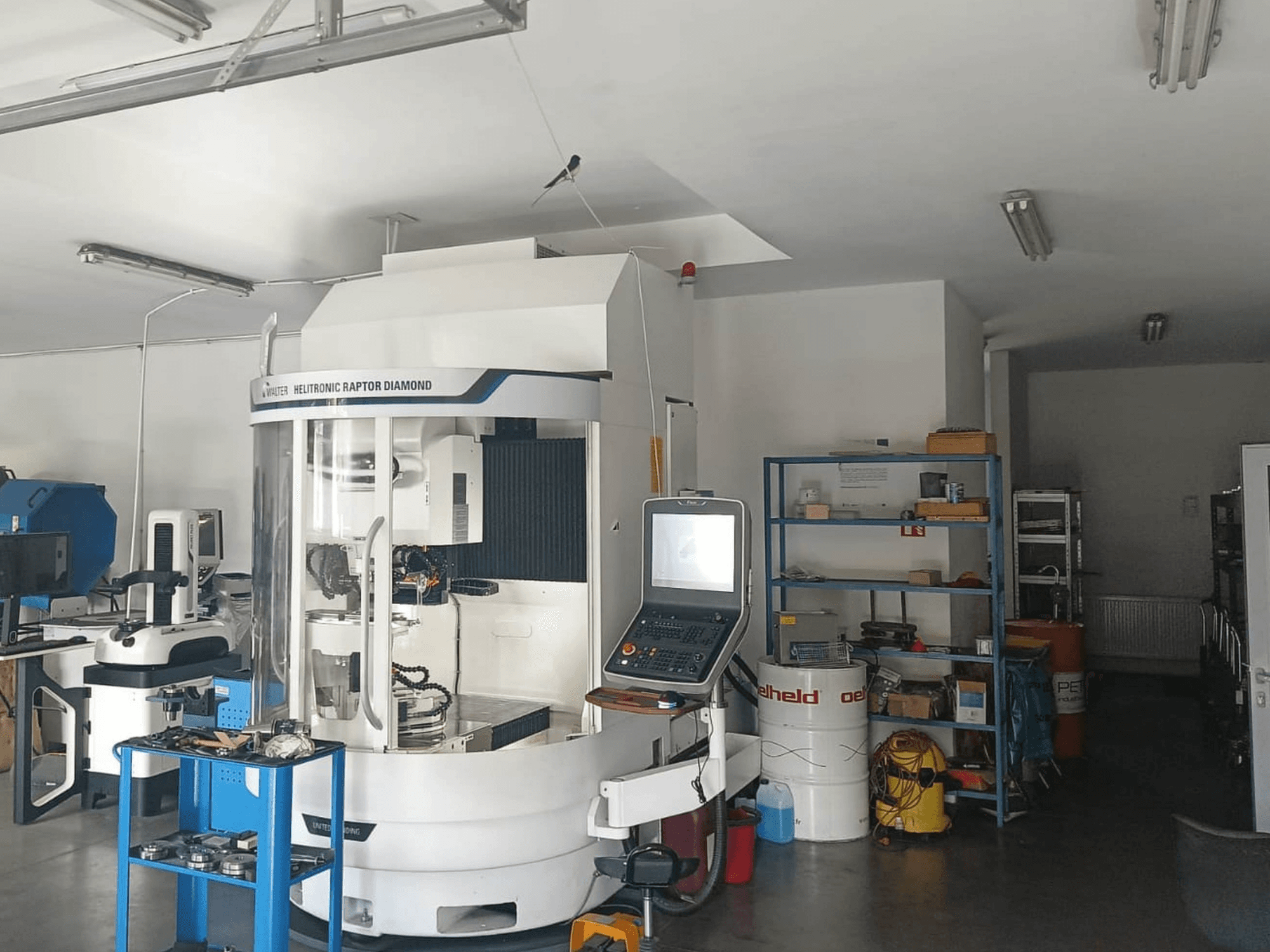 Máquina rectificadora cilíndrica WALTER HELITRONIC RAPTOR DIAMOND en un taller, vista lateral con el panel de control y las herramientas cerca.
