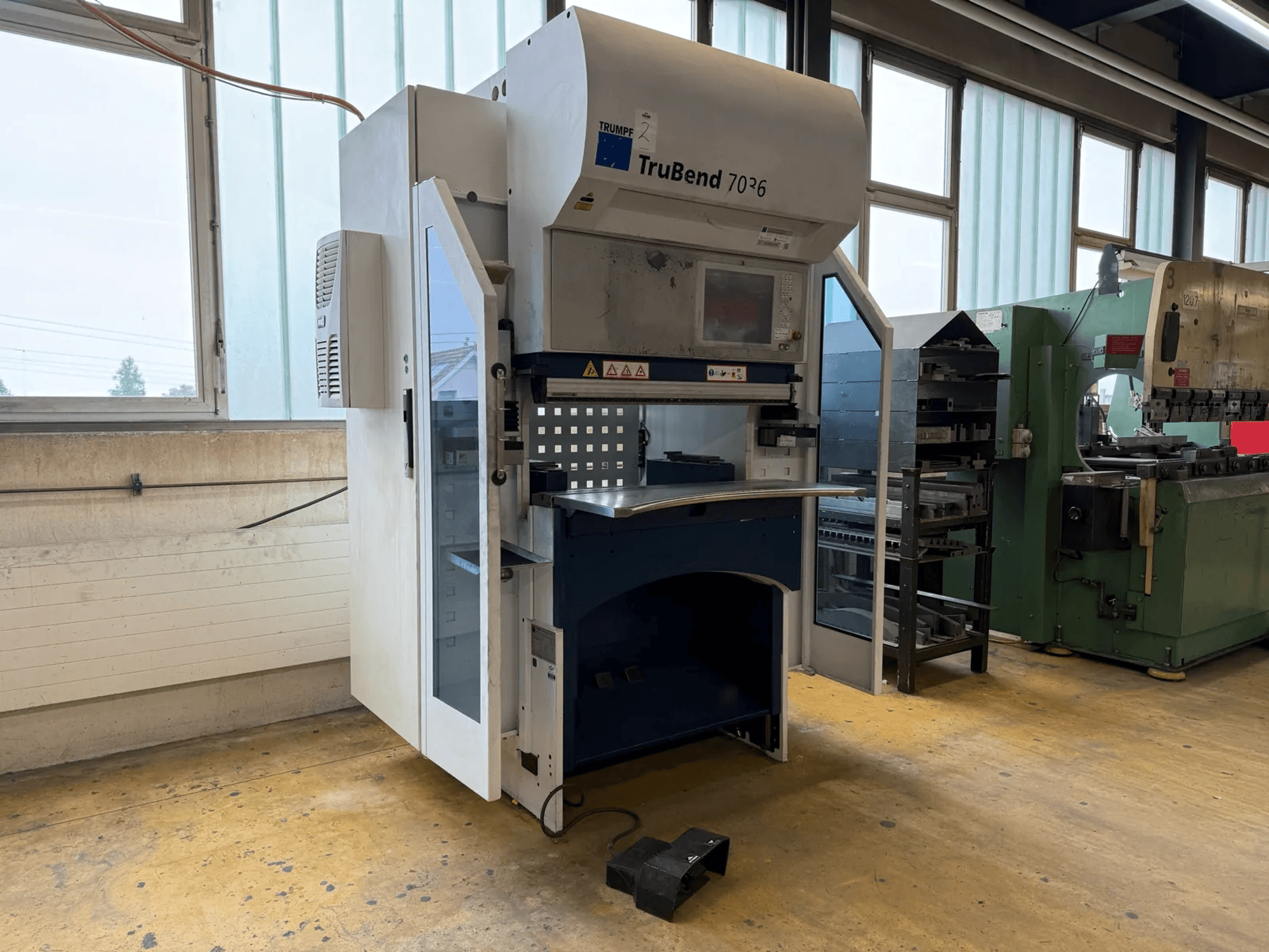 Plegadora TRUMPF TruBend 7036 en un taller, vista frontal con la puerta abierta, en la que se aprecian el panel de control y la zona de plegado.