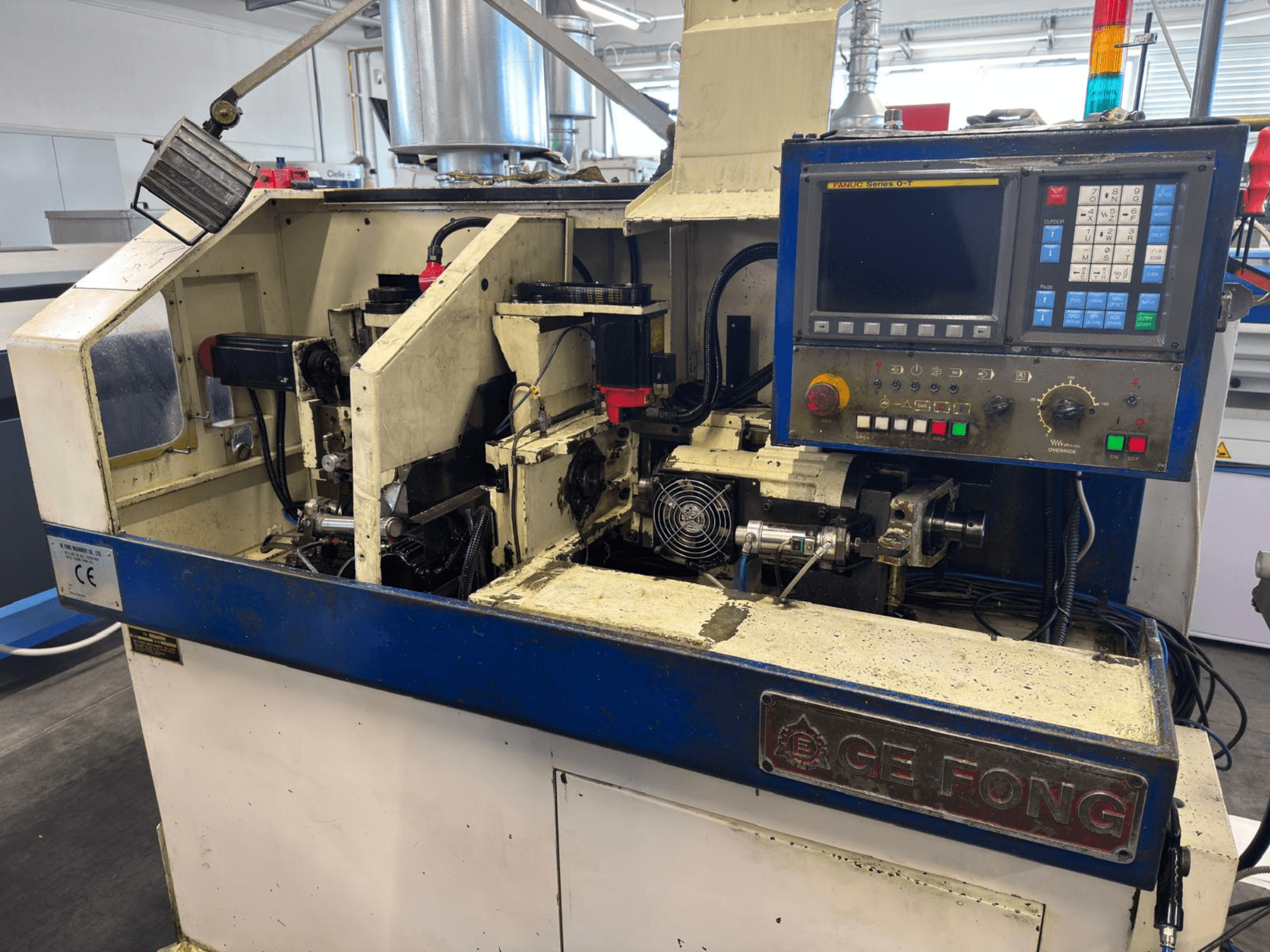 Máquina industrial GE FONG en vista frontal, mostrando los componentes internos, el panel de control y las piezas operativas.