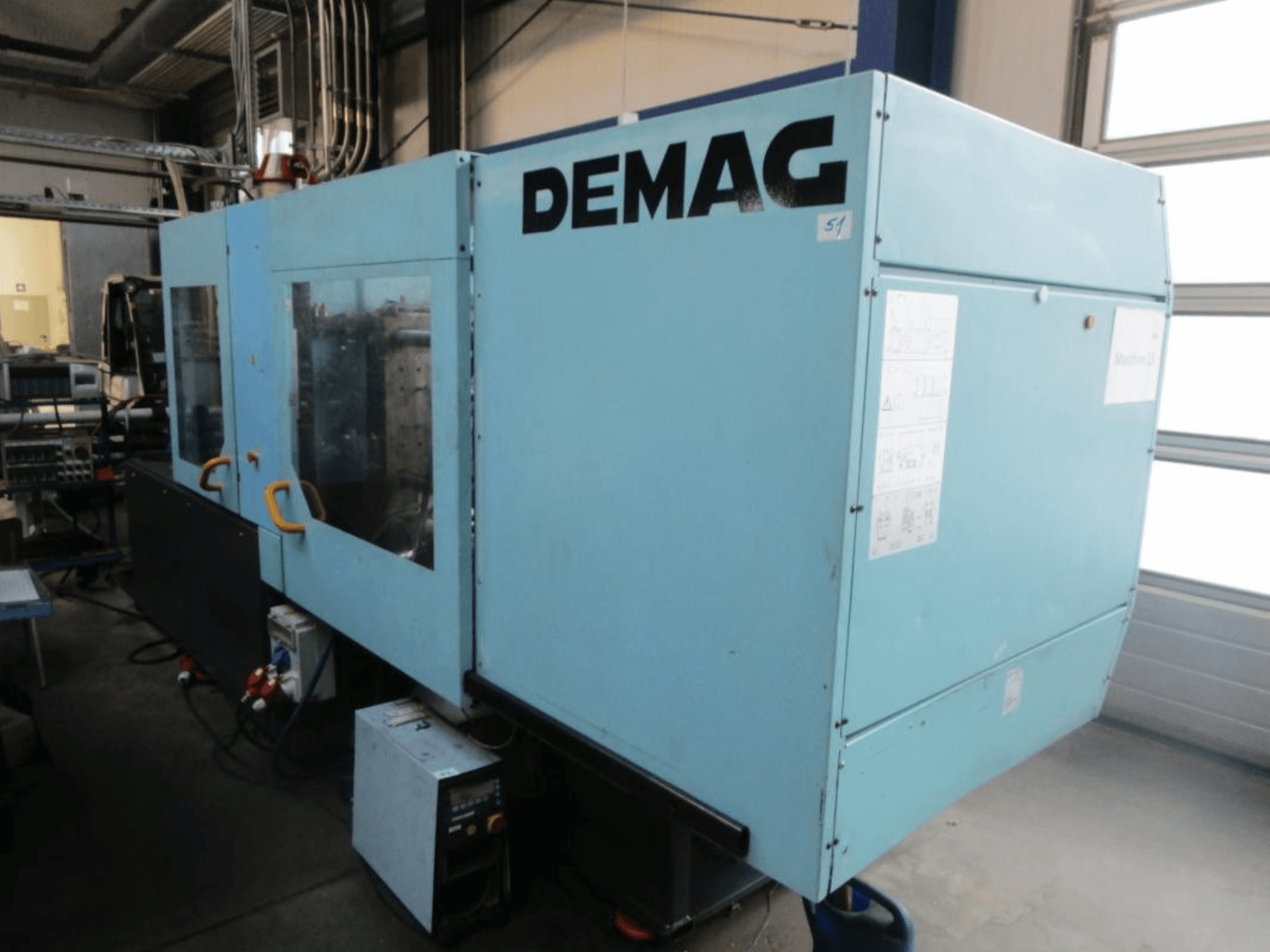 Vista frontal de una máquina de moldeo por inyección hidráulica DEMAG Ergotech 150-610 Viva, en la que se aprecian el panel de control y las palancas.