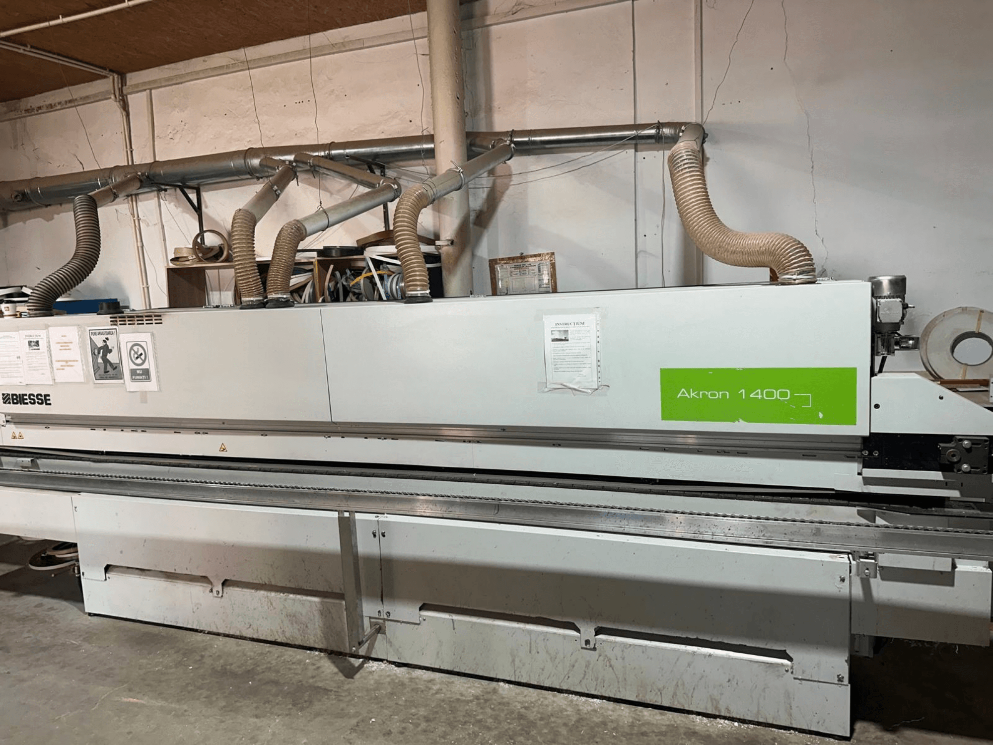 Máquina encintadora BIESSE Akron 1440 A vista lateral, en la que se aprecian los conductos de ventilación, el panel de control y las pegatinas de funcionamiento.