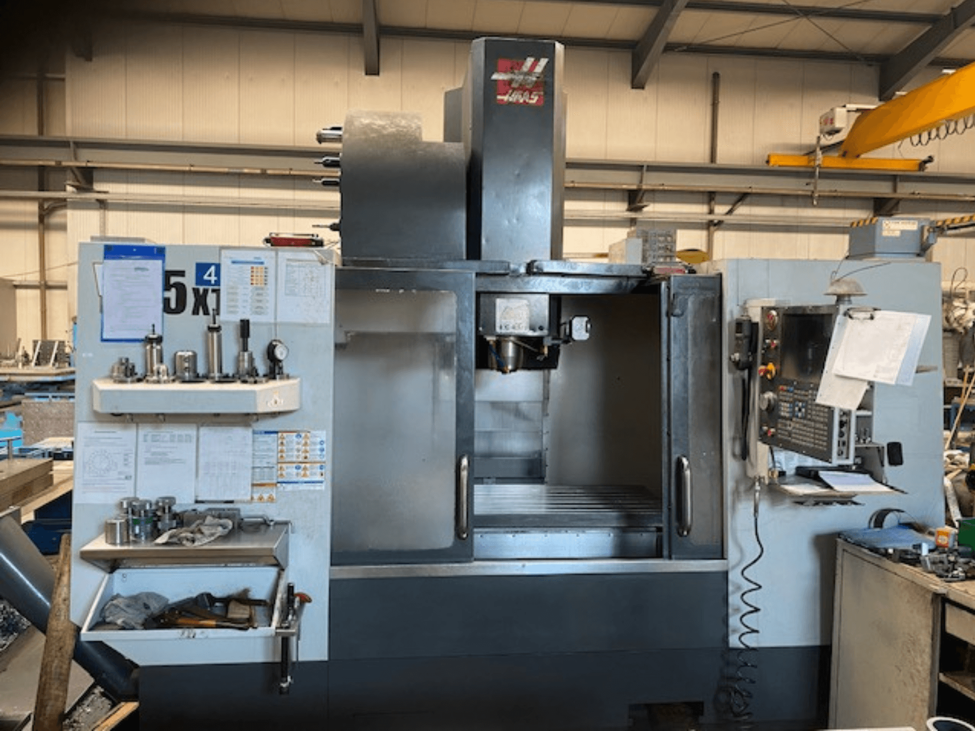 Centro de mecanizado vertical Haas VF-5, vista frontal, mostrando el panel de control, el almacenamiento de herramientas y la zona del husillo.