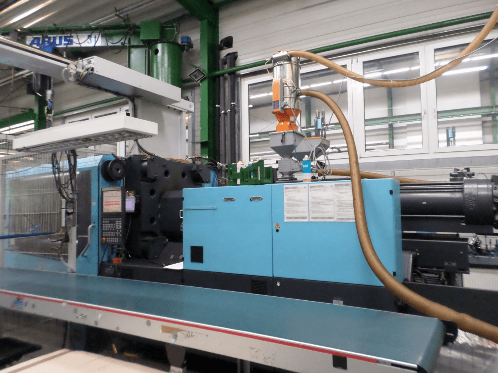 Vista frontal de una máquina de moldeo por inyección hidráulica DEMAG D 420, en la que se aprecian el panel de control, la tolva y los componentes hidráulicos.