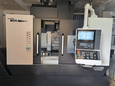 Máquina CNC Hyundai WIA F500 Plus en vista frontal, con panel de control digital y etiquetas de seguridad.