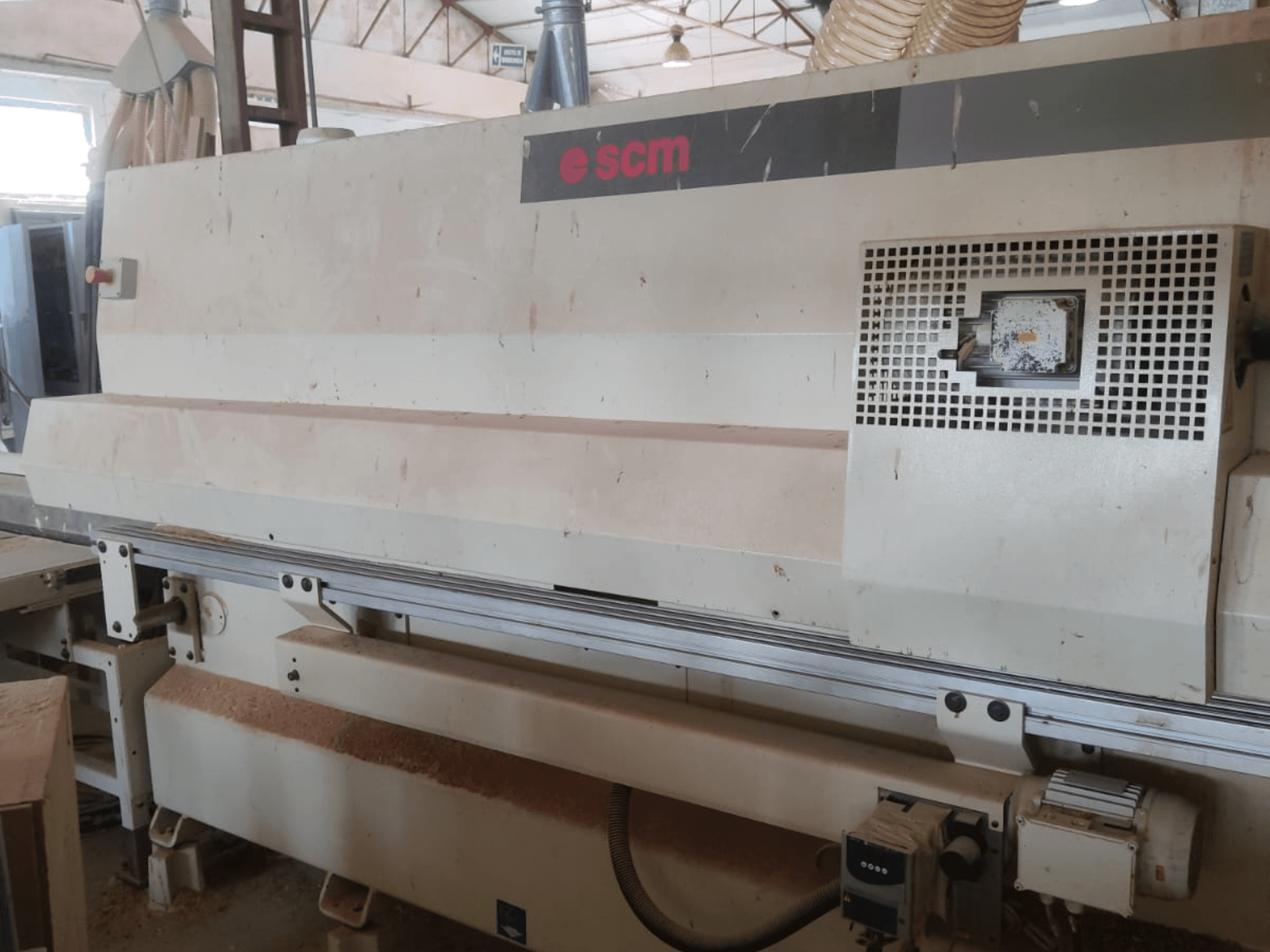 Centro de mecanizado de madera CNC SCM Windor60, vista frontal. Se aprecian los mandos de la máquina y el sistema de aspiración de polvo, con virutas de madera debajo.