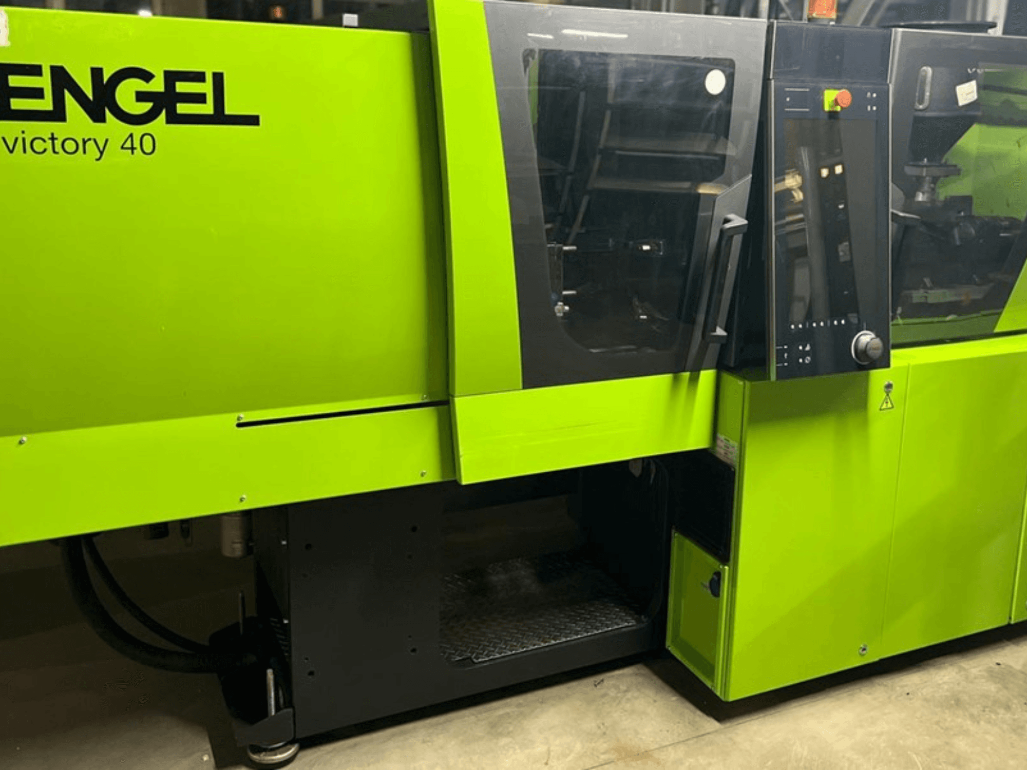 ENGEL Victory 40 máquina de moldeo por inyección en verde brillante, vista frontal mostrando el panel de control y la puerta de acceso con etiqueta de advertencia.