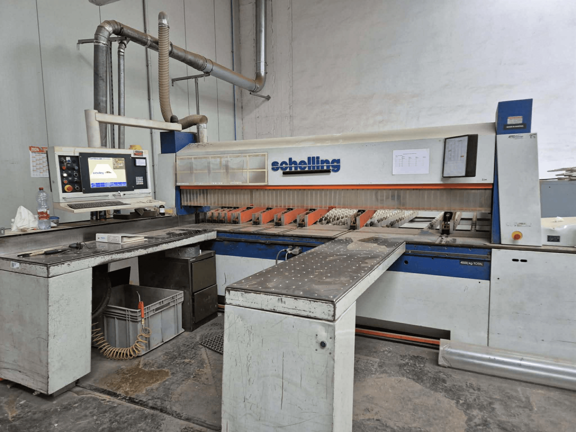 Máquina de corte Schaublin en vista lateral, con interfaz de ordenador, cuchillas afiladas y una robusta superficie de trabajo metálica.