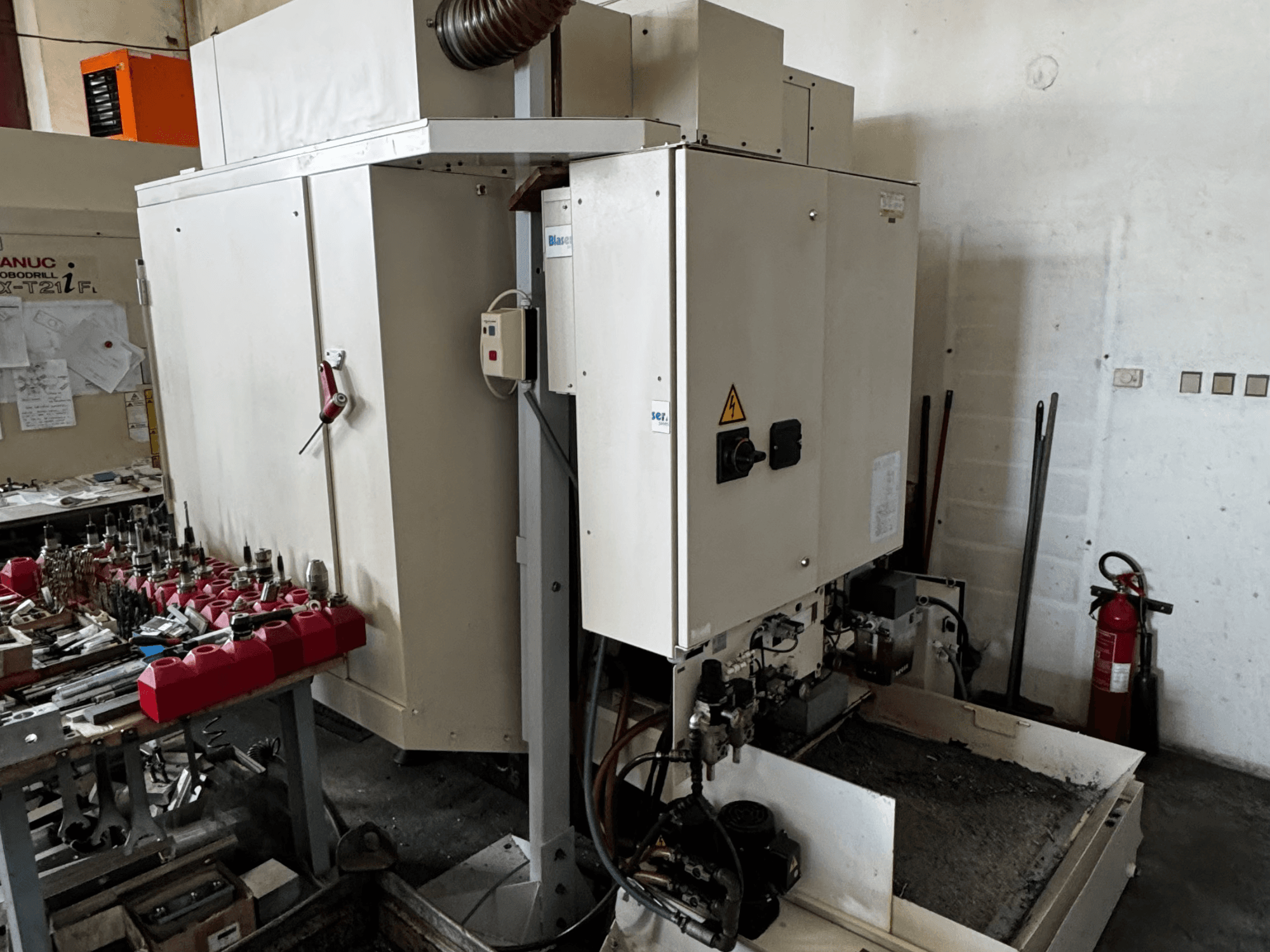 Centro de mecanizado vertical FANUC Robodrill alpha-T21iFL, vista lateral que muestra el panel de control, las herramientas y el espacio de trabajo.