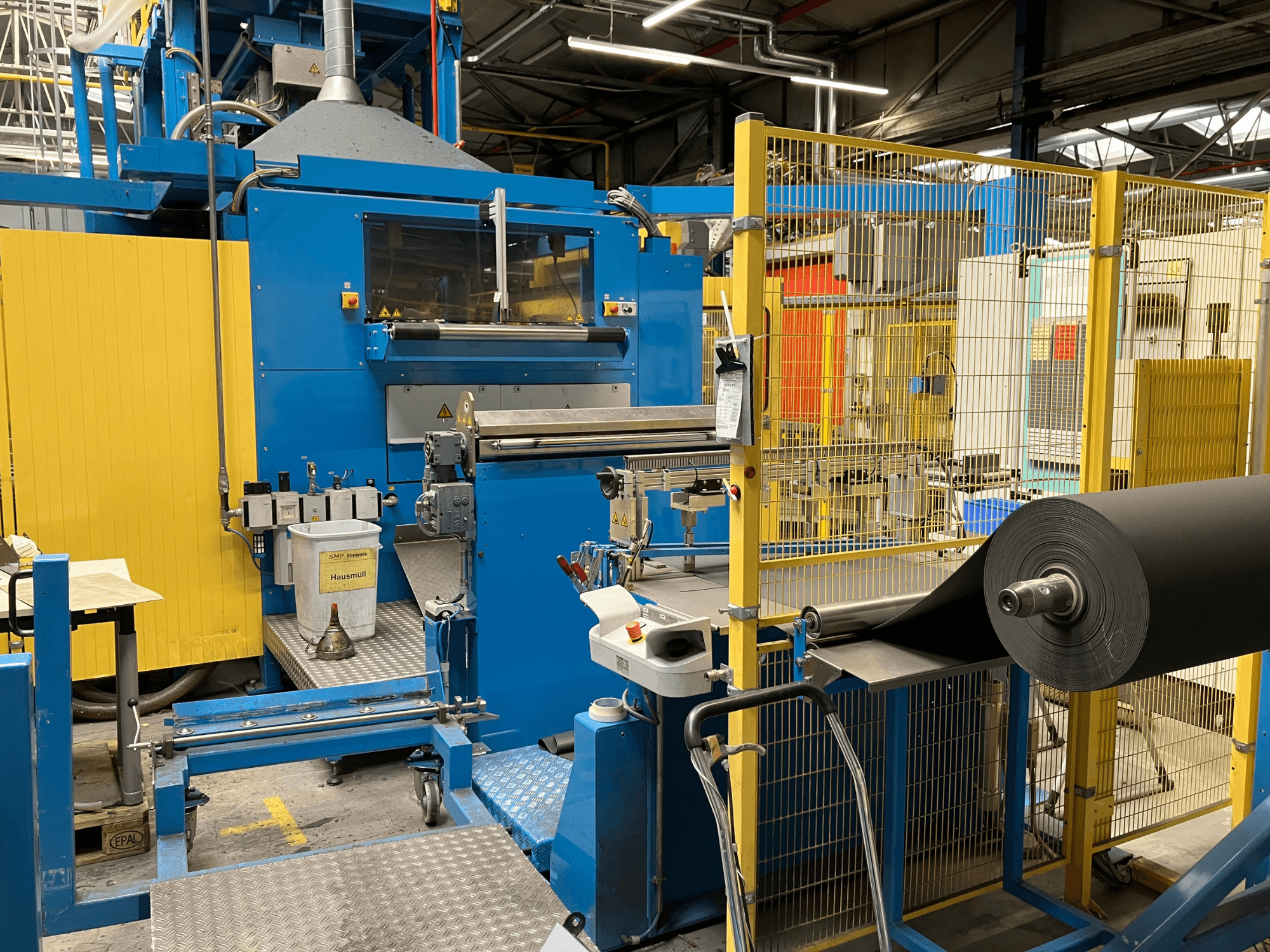 Máquina de transformación de plásticos KIEFEL KLS 86/235 vista de frente, con un rollo de material negro y panel de control.