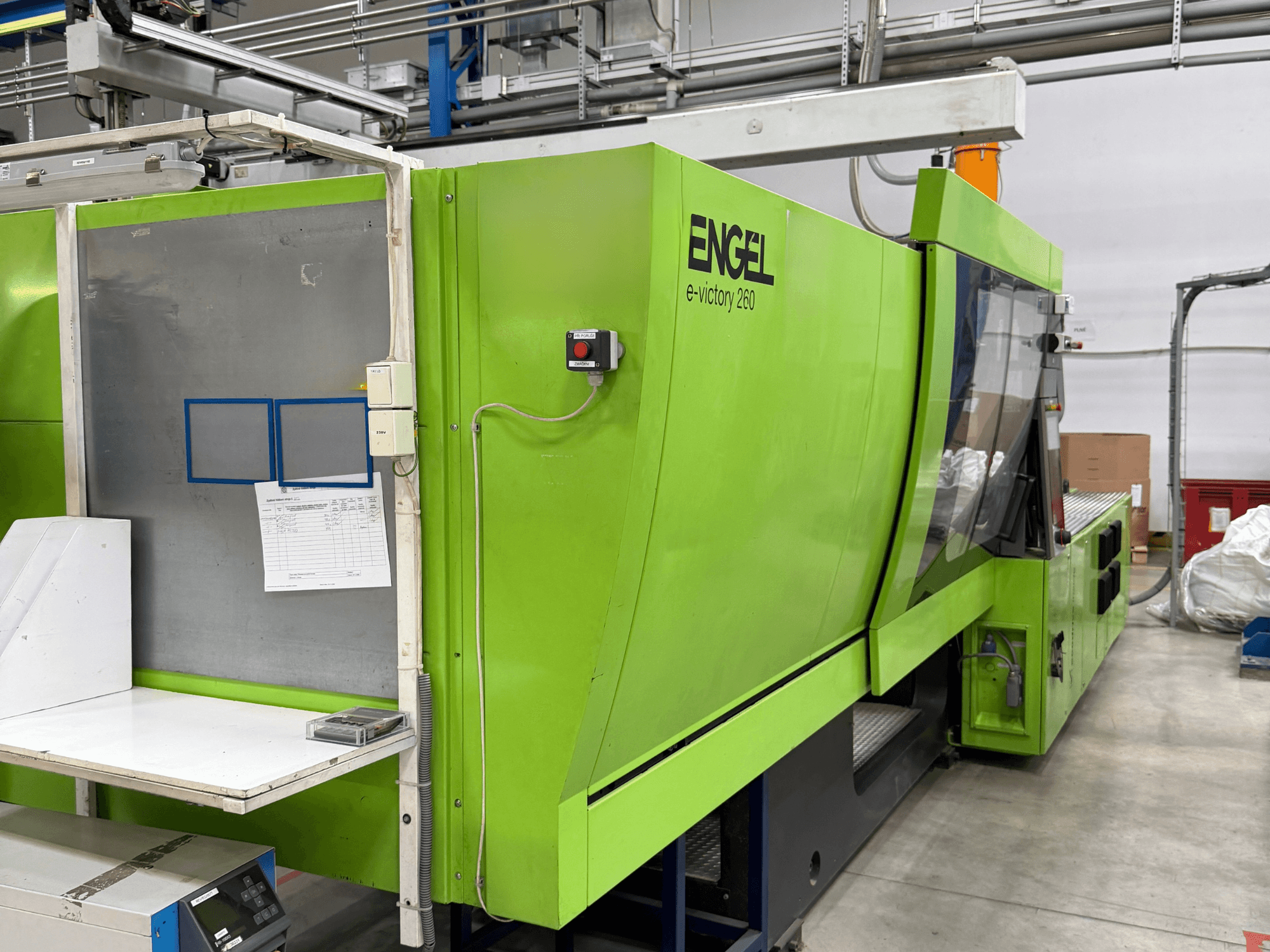 Máquina de moldeo por inyección eléctrica «Green Engel e-victory 260», vista desde un lateral, en la que se aprecian el panel de control y la superficie de trabajo.