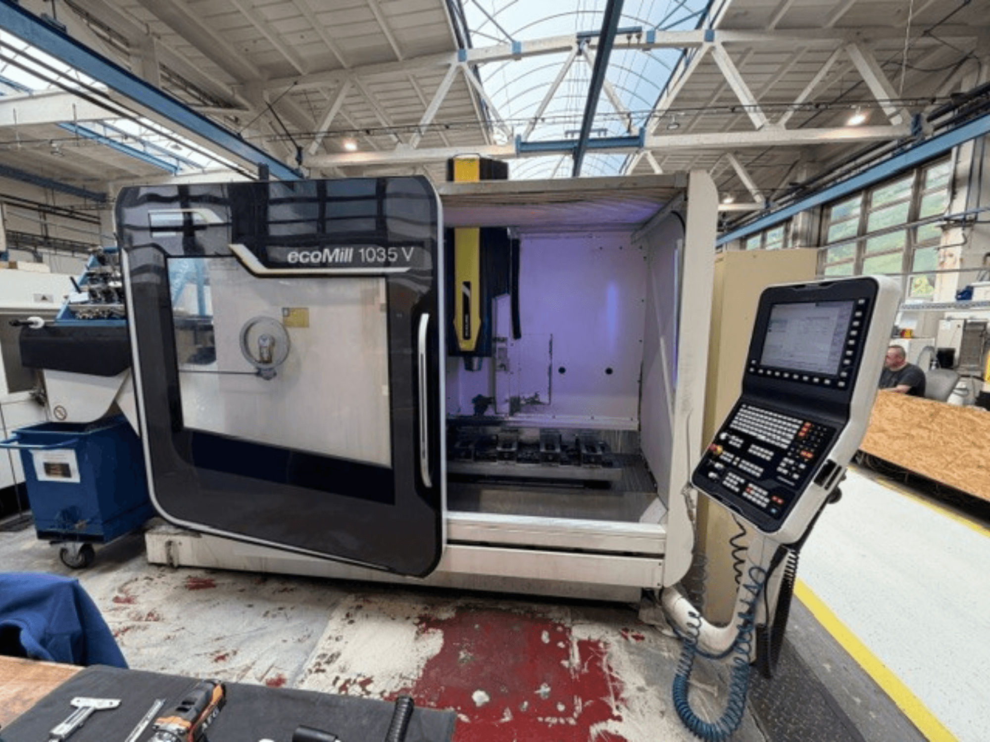 Vista frontal del centro de mecanizado vertical DMG MORI ecoMill 1035V con la puerta abierta, en la que se aprecian el panel de control y la zona de trabajo en el interior.