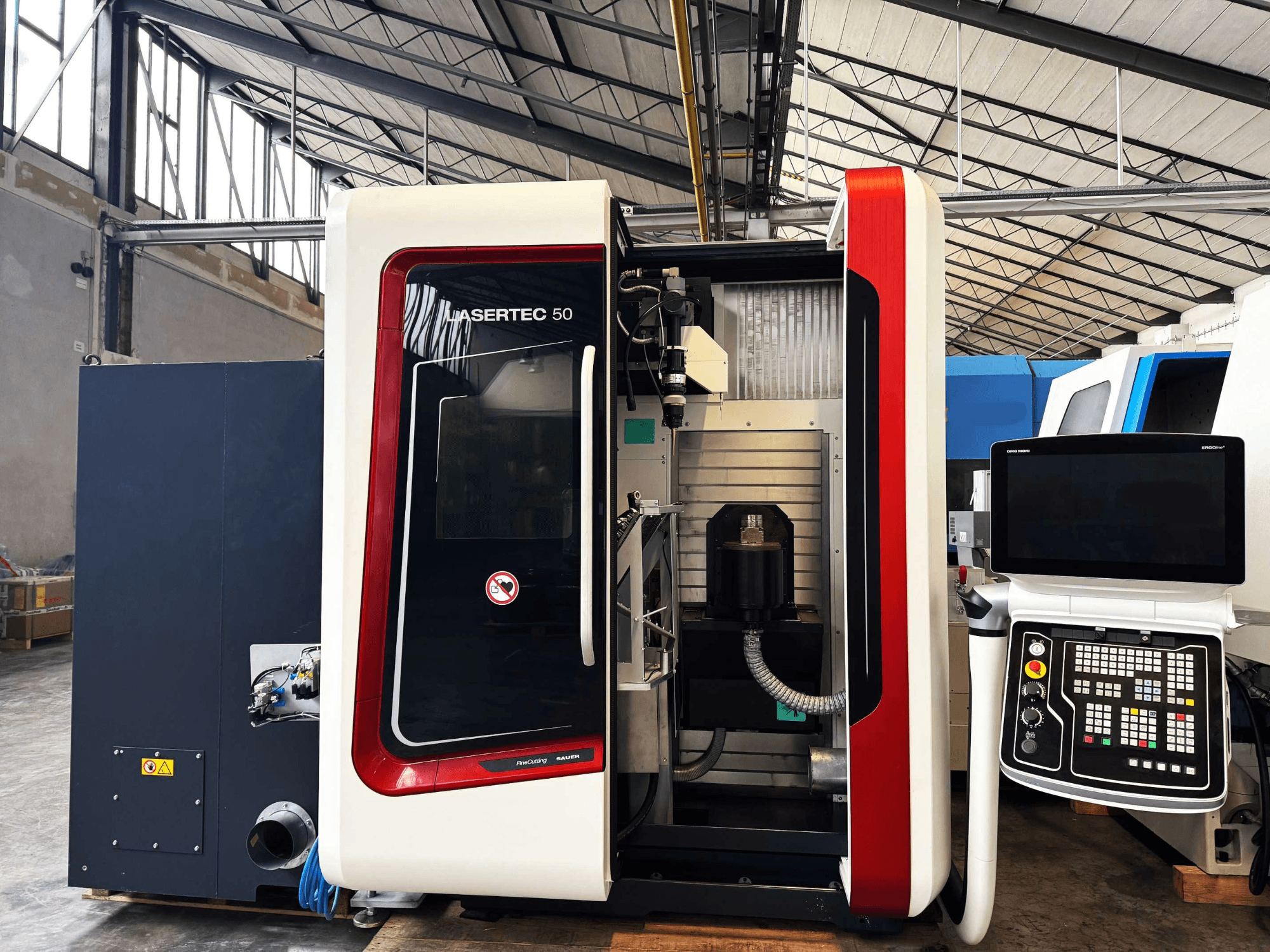 Máquina CNC LaserTec 50 en vista lateral, con panel de control en blanco y negro, portaherramientas visible y configuración industrial.