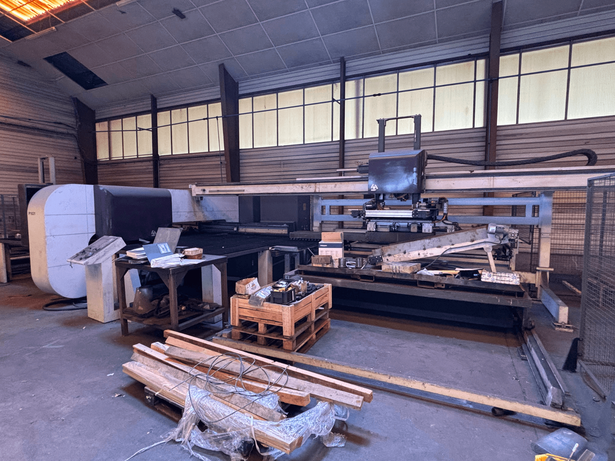 Punzonadora CNC DANOBAT P1631 en un taller, vista frontal, rodeada de materiales y herramientas en un suelo desordenado.